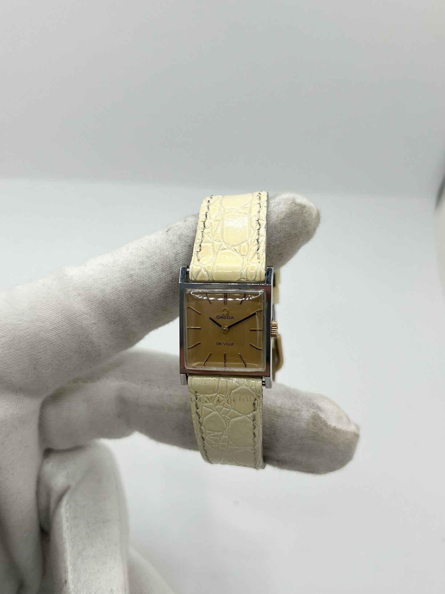 Montre Omega De Ville 511.087 vintage pour femme en acier, fabriquée en 1966. Cette montre élégante est dotée d'un cadran champagne avec index bâtons, d'un mouvement à remontage manuel calibre 620 et d'un verre en plexiglas. Elle est montée sur un bracelet en cuir beige avec boucle ardillon en acier. Son format de 19,5 mm lui confère une allure raffinée et intemporelle. Montre de collection en très bon état d'occasion, révisée et prête à être portée.