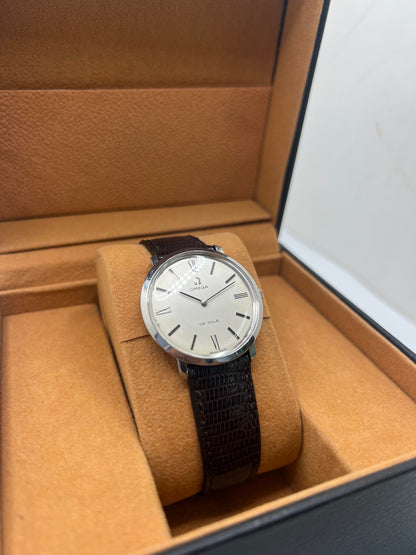 Montre Omega De Ville vintage référence 111.077 en acier, fabriquée en 1969. Ce modèle à remontage manuel est doté d'un cadran argent avec chiffres romains, d'un verre en plexiglas et d'un boîtier de 33 mm. Le bracelet en cuir noir avec boucle ardillon en acier complète son style classique et intemporel. Cette montre d'occasion révisée séduit les amateurs d'horlogerie vintage et de montres Omega de collection.
