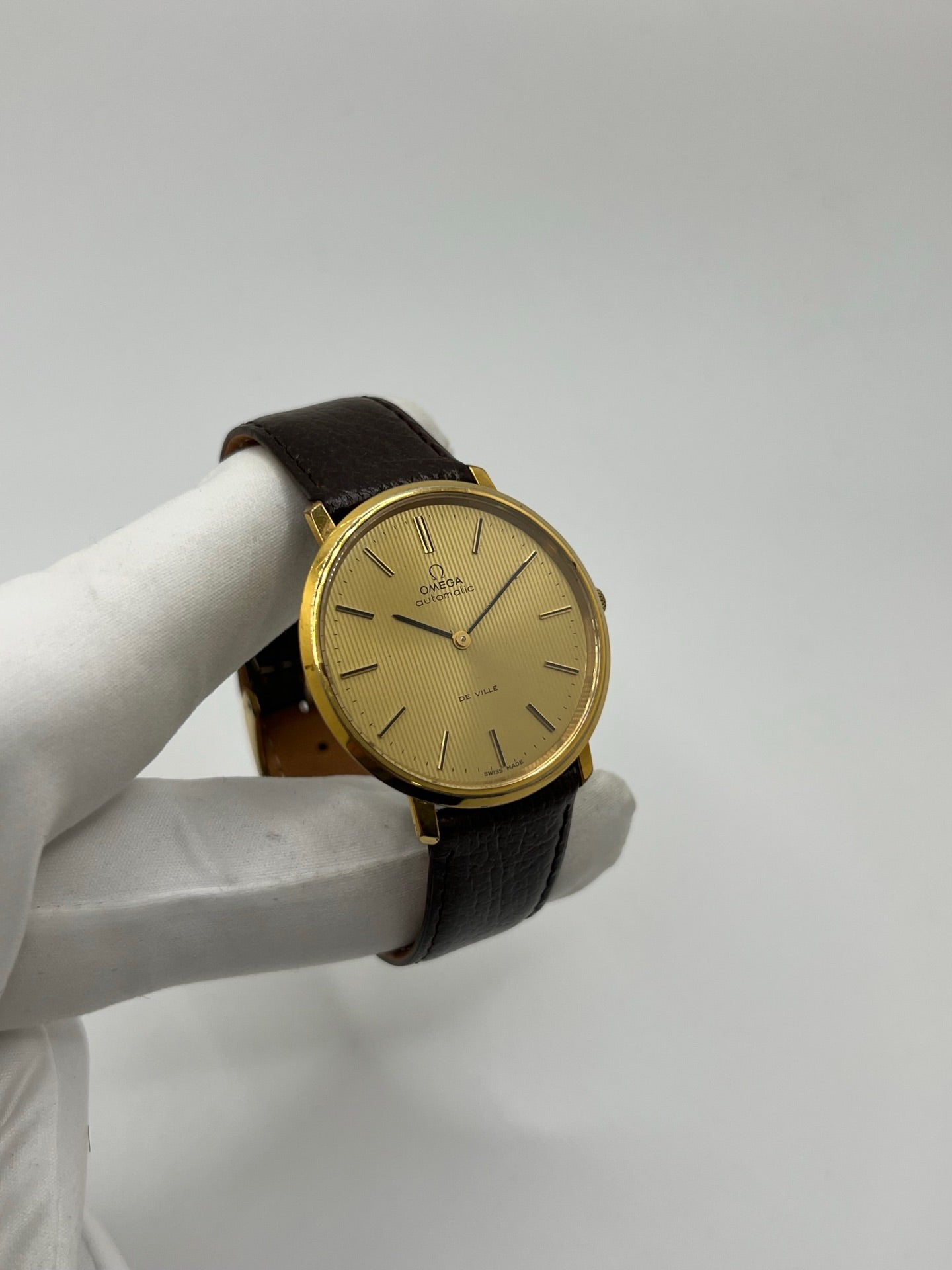 Montre Omega De Ville référence 151.0039 vintage de 1973 en acier avec mouvement automatique calibre 711, cadran doré et bracelet en cuir noir. Ce modèle homme ou unisexe de 35,5 mm présente un design élégant et intemporel. Montre d’occasion en très bon état, révisée en interne le 13 mars 2026, avec légères traces d’usure discrètes. Pièce classique de collection sans coffret ni papiers d’origine.