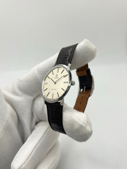 Montre Omega De Ville vintage référence 111.077 en acier, fabriquée en 1969. Ce modèle à remontage manuel est doté d'un cadran argent avec chiffres romains, d'un verre en plexiglas et d'un boîtier de 33 mm. Le bracelet en cuir noir avec boucle ardillon en acier complète son style classique et intemporel. Cette montre d'occasion révisée séduit les amateurs d'horlogerie vintage et de montres Omega de collection.
