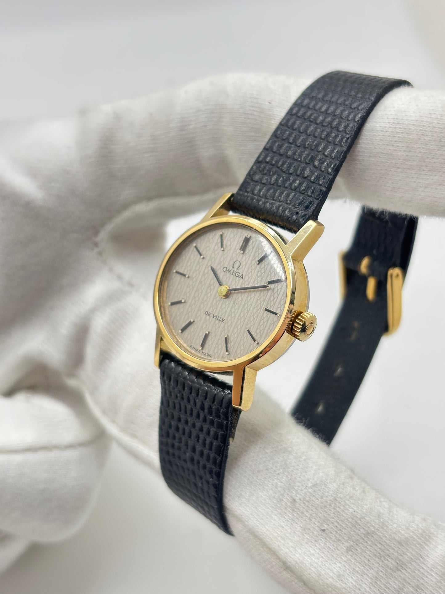 Montre Omega De Ville vintage référence 511.0508 pour femme, datant de 1967, avec boîtier en acier de 24 mm et cadran gris à index bâtons. Cette montre à remontage manuel est équipée du calibre Omega 625 à 17 rubis et est montée sur un bracelet en cuir noir avec boucle ardillon en acier. Révisée et en très bon état, elle présente de légères traces d'usure conformes à son âge. Une montre de collection au design élégant, idéale pour les amateurs d'horlogerie vintage.
