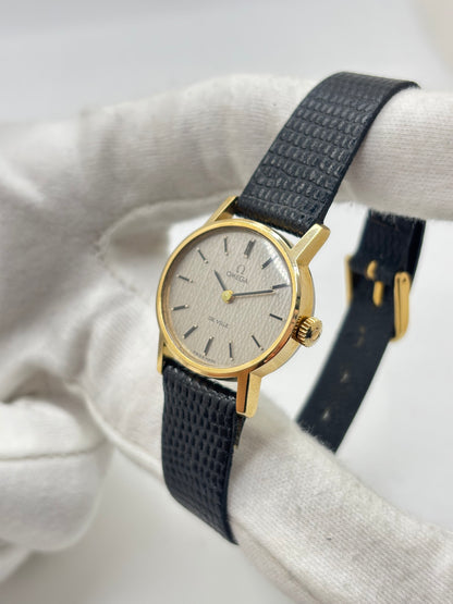 Montre Omega De Ville vintage référence 511.0508 pour femme, datant de 1967, avec boîtier en acier de 24 mm et cadran gris à index bâtons. Cette montre à remontage manuel est équipée du calibre Omega 625 à 17 rubis et est montée sur un bracelet en cuir noir avec boucle ardillon en acier. Révisée et en très bon état, elle présente de légères traces d'usure conformes à son âge. Une montre de collection au design élégant, idéale pour les amateurs d'horlogerie vintage.
