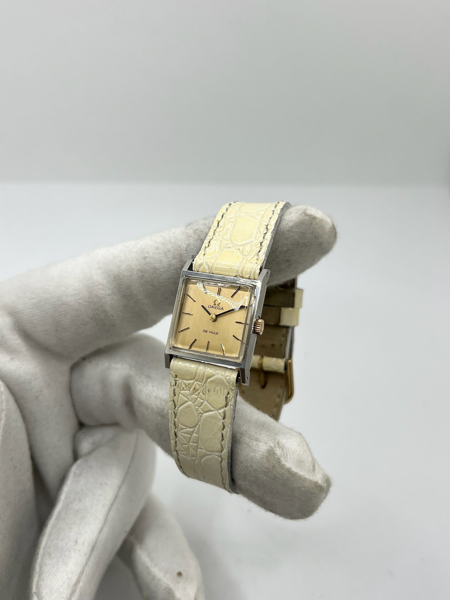 Montre Omega De Ville 511.087 vintage pour femme en acier, fabriquée en 1966. Cette montre élégante est dotée d'un cadran champagne avec index bâtons, d'un mouvement à remontage manuel calibre 620 et d'un verre en plexiglas. Elle est montée sur un bracelet en cuir beige avec boucle ardillon en acier. Son format de 19,5 mm lui confère une allure raffinée et intemporelle. Montre de collection en très bon état d'occasion, révisée et prête à être portée.