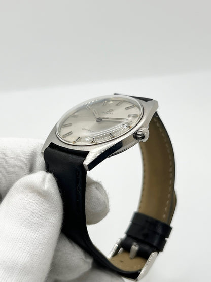 Montre Omega Genève 135.041 vintage de 1969, équipée d’un mouvement à remontage manuel avec calibre 601, offrant une réserve de marche de 48 heures. Son boîtier en acier de 34 mm est associé à un cadran argent à index bâtons, protégé par un verre Plexiglas. Cette Omega Genève est montée sur un bracelet noir en cuir de vache avec boucle ardillon en acier. En bon état, elle présente des traces d’usure visibles.
