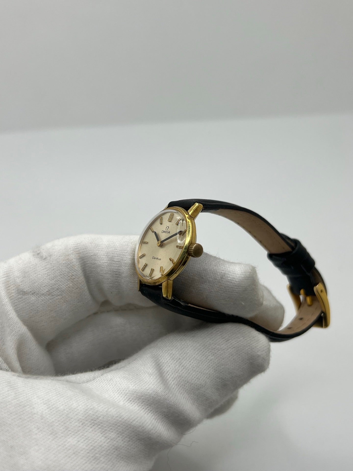 Montre Omega Genève femme vintage de 1972 en plaqué or, avec mouvement à remontage manuel. Boîtier de 23 mm au cadran doré orné de pierres précieuses et verre en plastique. Bracelet en cuir noir avec boucle en acier. Modèle élégant et intemporel, en bon état avec traces d’usure visibles. Révisée en avril 2026, vendue sans coffret ni papiers, disponible en stock en France.