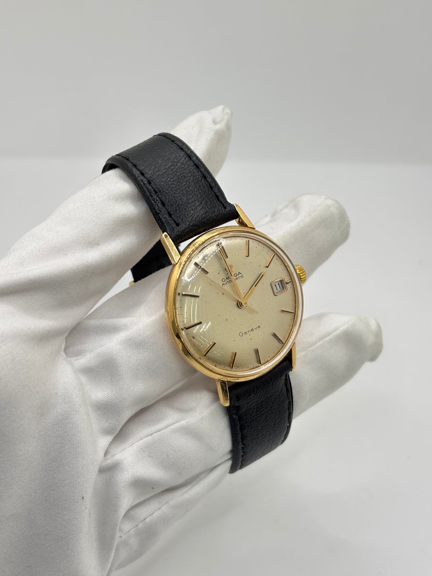 Montre Omega Genève vintage en or jaune 18 carats, référence 162.3009, équipée d’un mouvement automatique calibre 565. Boîtier de 35 mm avec cadran doré à index bâtons et verre plexiglas. Bracelet en cuir noir avec boucle acier. Modèle homme/unisexe fabriqué en 1967, au style classique et élégant. Montre d’occasion avec traces d’usure visibles, révisée en avril 2026, idéale pour collectionneurs et amateurs d’horlogerie ancienne.