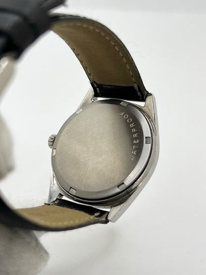 Montre Omega Genève 135.041 vintage de 1969, équipée d’un mouvement à remontage manuel avec calibre 601, offrant une réserve de marche de 48 heures. Son boîtier en acier de 34 mm est associé à un cadran argent à index bâtons, protégé par un verre Plexiglas. Cette Omega Genève est montée sur un bracelet noir en cuir de vache avec boucle ardillon en acier. En bon état, elle présente des traces d’usure visibles.