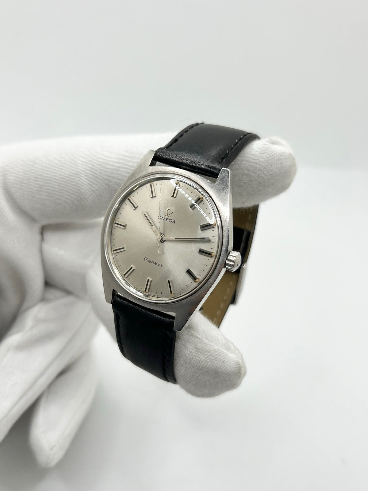 Montre Omega Genève 135.041 vintage de 1969, équipée d’un mouvement à remontage manuel avec calibre 601, offrant une réserve de marche de 48 heures. Son boîtier en acier de 34 mm est associé à un cadran argent à index bâtons, protégé par un verre Plexiglas. Cette Omega Genève est montée sur un bracelet noir en cuir de vache avec boucle ardillon en acier. En bon état, elle présente des traces d’usure visibles.
