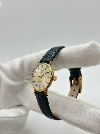 Montre Omega Genève vintage référence 511.0457 pour femme, fabriquée vers 1972 et équipée d'un mouvement à remontage manuel. Son boîtier en acier de 23 mm est associé à un cadran blanc à index bâtons protégé par un verre en matière plastique. Elle est montée sur un bracelet en cuir vert avec boucle ardillon en acier. Révisée en interne et proposée en très bon état, cette montre d'occasion incarne l'élégance discrète et le savoir-faire horloger suisse des années 1970.