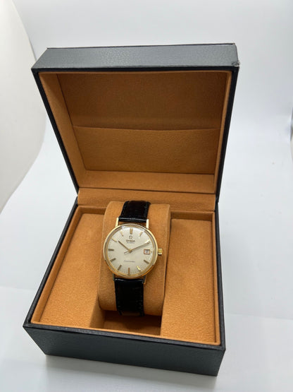Montre Omega Seamaster DeVille vintage de 1961 en or jaune 14 carats, équipée d’un mouvement automatique calibre 560. Boîtier rond de 34 mm avec verre plexiglas, cadran champagne à index bâtons et date. Bracelet en cuir de crocodile noir avec boucle en or. Montre homme élégante et intemporelle, en bon état avec traces d’usure, récemment révisée, idéale pour collection ou usage quotidien.