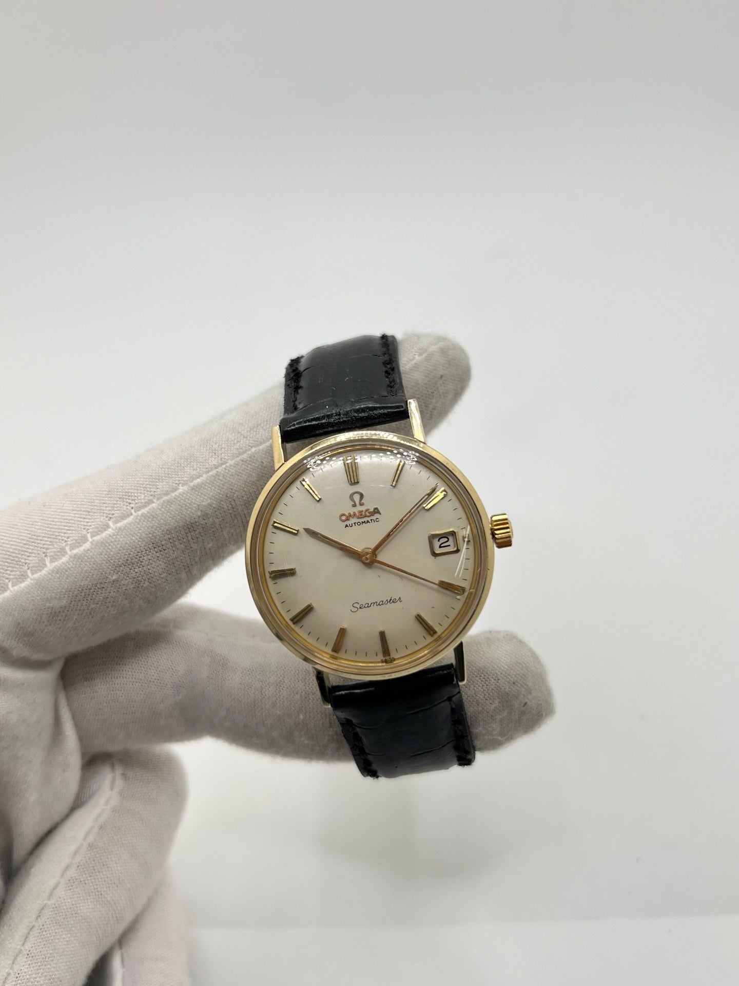 Montre Omega Seamaster DeVille vintage de 1961 en or jaune 14 carats, équipée d’un mouvement automatique calibre 560. Boîtier rond de 34 mm avec verre plexiglas, cadran champagne à index bâtons et date. Bracelet en cuir de crocodile noir avec boucle en or. Montre homme élégante et intemporelle, en bon état avec traces d’usure, récemment révisée, idéale pour collection ou usage quotidien.
