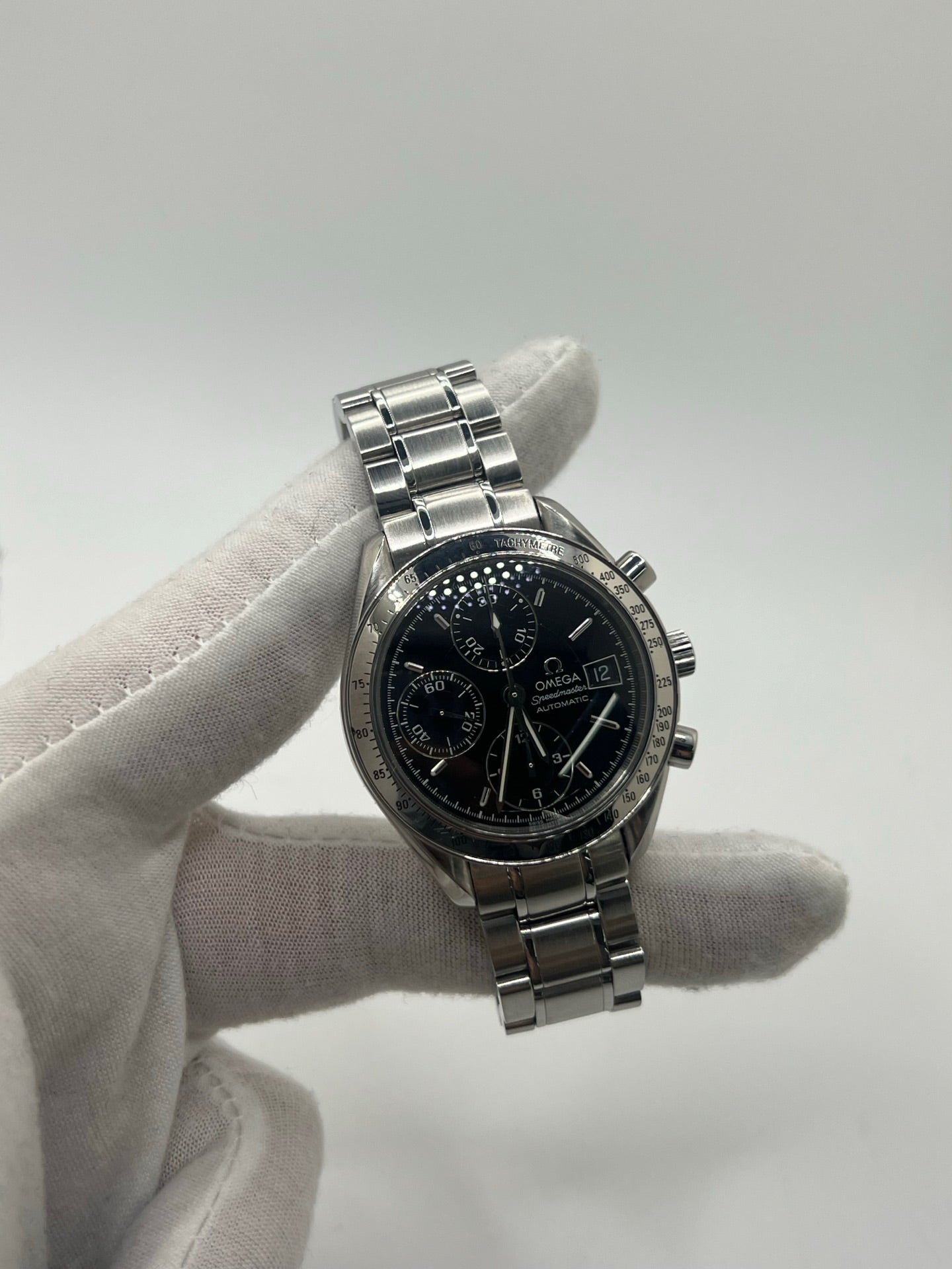 Montre Omega Speedmaster Date référence 3513.50 en acier, chronographe automatique avec boîtier de 39 mm et bracelet en acier assorti. Cadran noir sobre sans chiffres, protégé par un verre saphir, avec affichage de la date et fonctions chronographe. Modèle étanche 5 ATM, animé par le calibre automatique 1152 offrant 44 heures de réserve de marche. Montre homme élégante et sportive, emblématique de la collection Speedmaster.