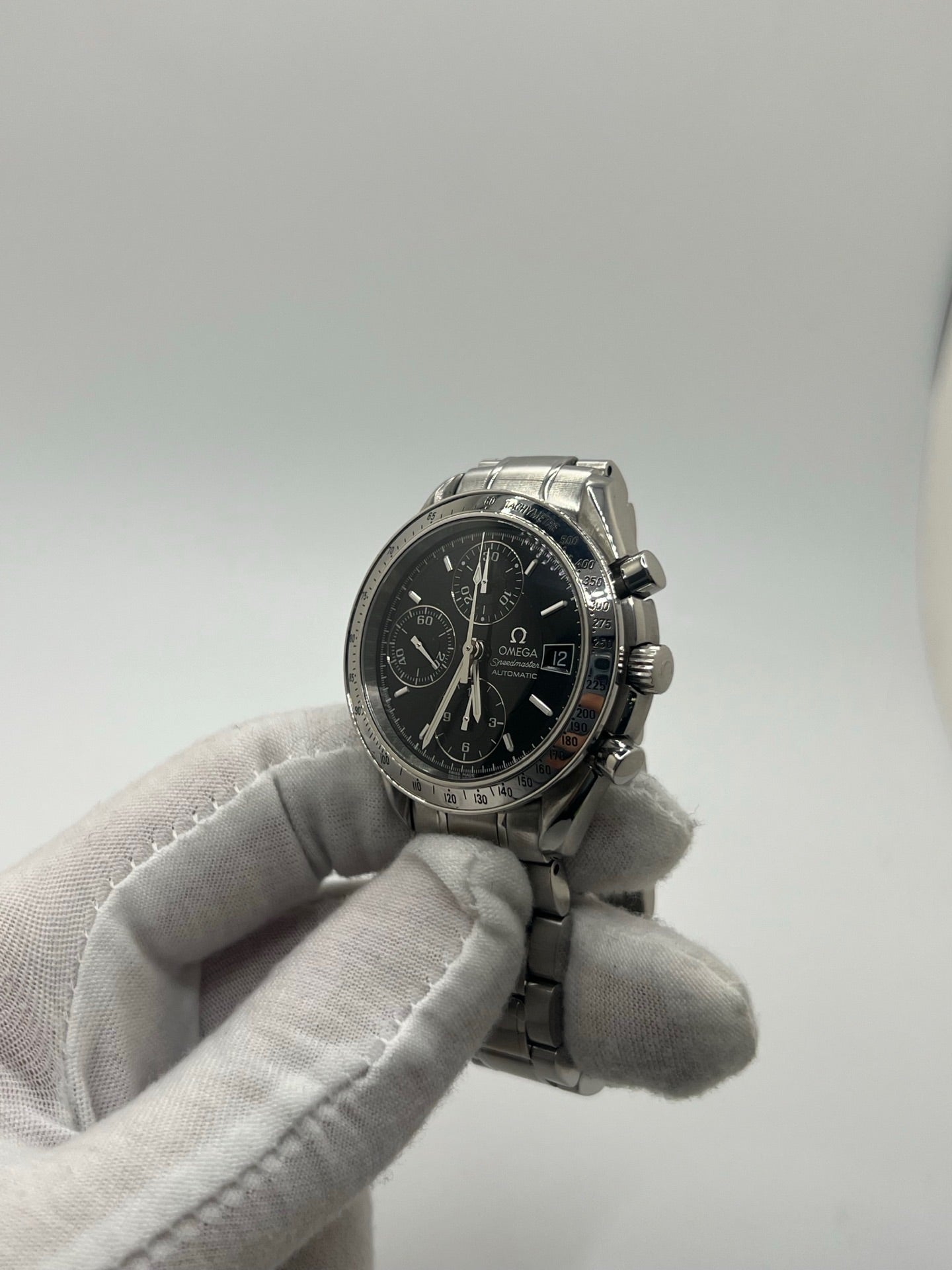 Montre Omega Speedmaster Date référence 3513.50 en acier, chronographe automatique avec boîtier de 39 mm et bracelet en acier assorti. Cadran noir sobre sans chiffres, protégé par un verre saphir, avec affichage de la date et fonctions chronographe. Modèle étanche 5 ATM, animé par le calibre automatique 1152 offrant 44 heures de réserve de marche. Montre homme élégante et sportive, emblématique de la collection Speedmaster.