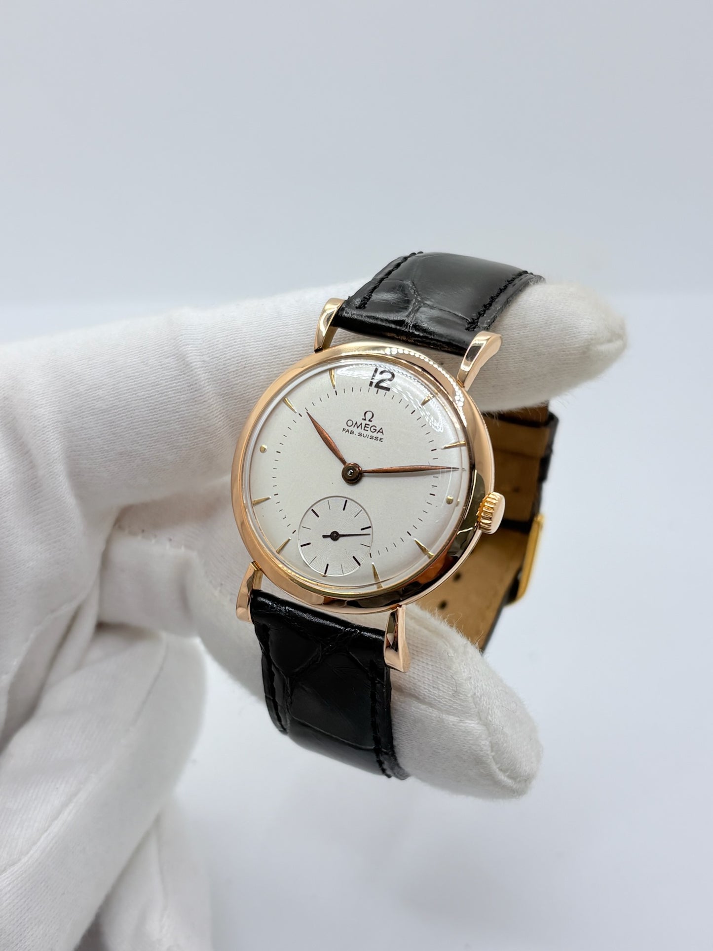 Montre Omega Vintage équipée du célèbre calibre mécanique 30T2 à remontage manuel. Cette montre ancienne, datant approximativement de 1948, présente un boîtier en or rose de 33 mm et un élégant cadran blanc à index bâtons. Son bracelet en cuir de crocodile noir complète son esthétique classique et intemporelle. Cette Omega Vintage calibre 30T2 incarne le charme d’une montre de collection, alliant savoir-faire horloger, élégance et authenticité.