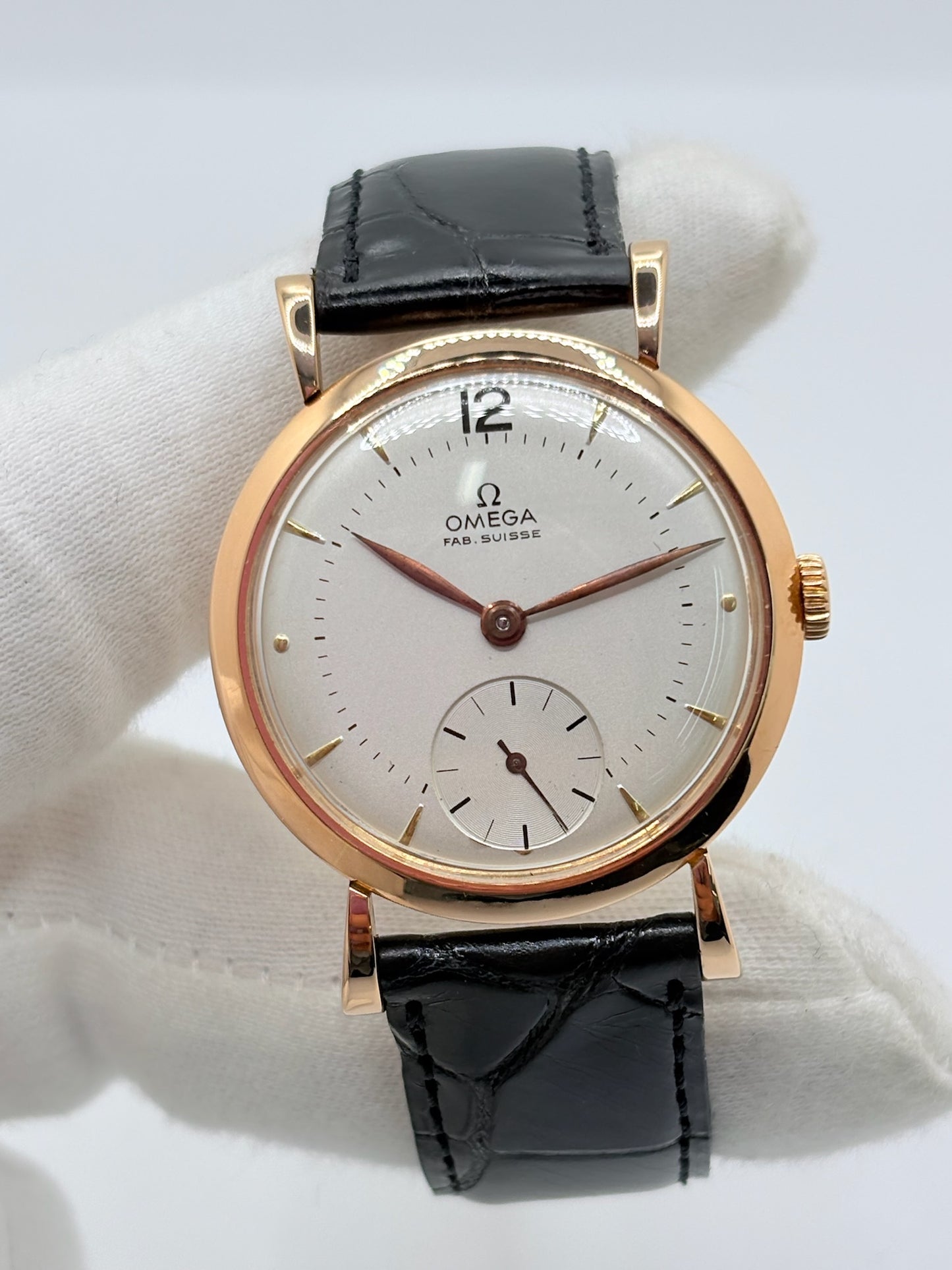 Montre Omega Vintage équipée du célèbre calibre mécanique 30T2 à remontage manuel. Cette montre ancienne, datant approximativement de 1948, présente un boîtier en or rose de 33 mm et un élégant cadran blanc à index bâtons. Son bracelet en cuir de crocodile noir complète son esthétique classique et intemporelle. Cette Omega Vintage calibre 30T2 incarne le charme d’une montre de collection, alliant savoir-faire horloger, élégance et authenticité.
