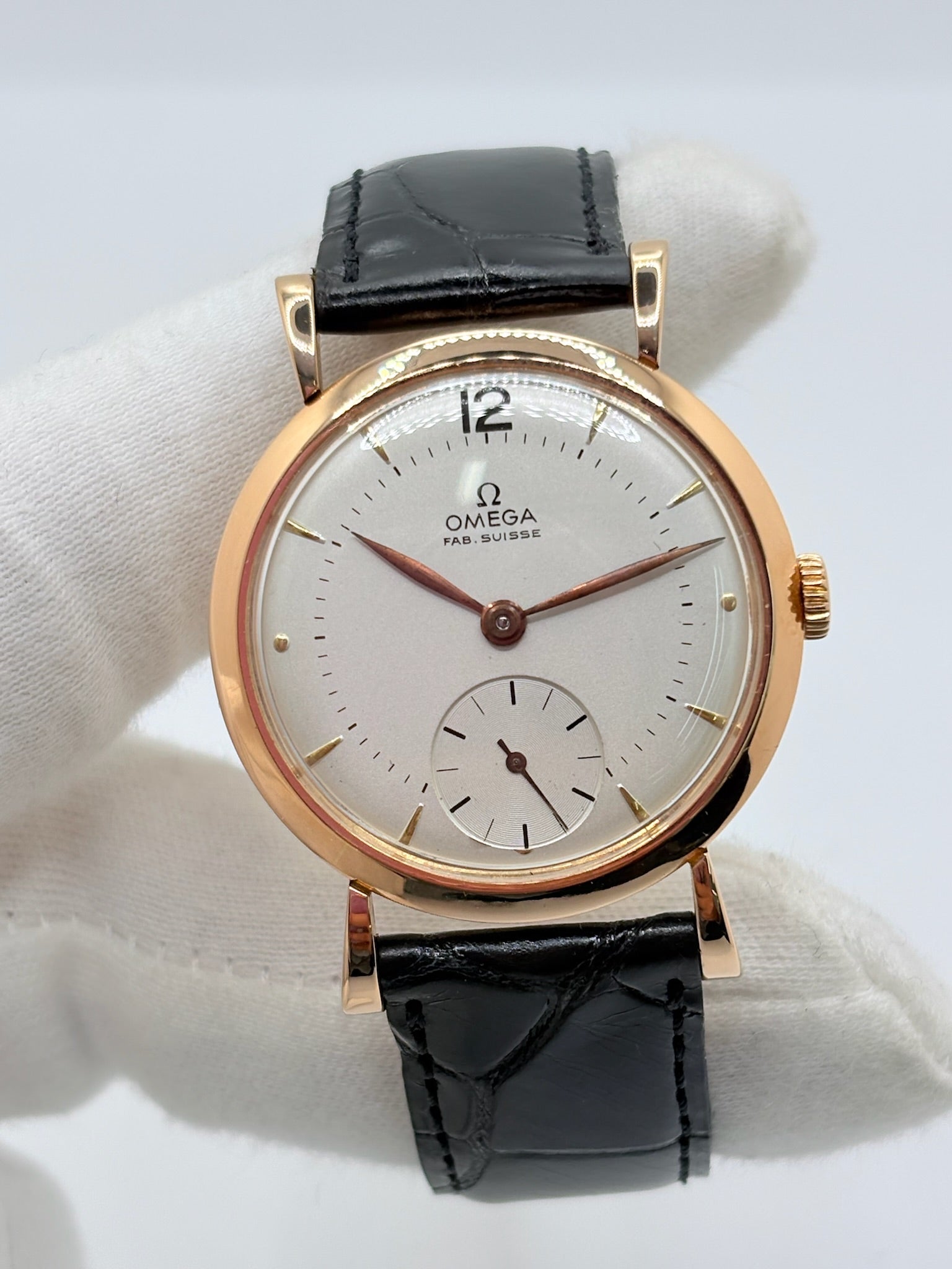 Montre Omega Vintage équipée du célèbre calibre mécanique 30T2 à remontage manuel. Cette montre ancienne, datant approximativement de 1948, présente un boîtier en or rose de 33 mm et un élégant cadran blanc à index bâtons. Son bracelet en cuir de crocodile noir complète son esthétique classique et intemporelle. Cette Omega Vintage calibre 30T2 incarne le charme d’une montre de collection, alliant savoir-faire horloger, élégance et authenticité.