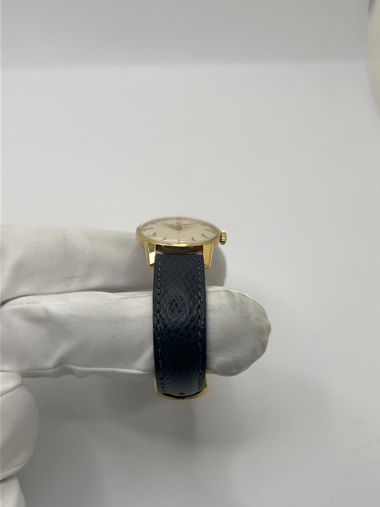 Montre femme Omega Classic vintage de 1961 en plaqué or, équipée d’un mouvement à remontage manuel. Boîtier de 25 mm avec cadran blanc à index bâtons sous verre plexiglas. Bracelet en cuir noir avec boucle ardillon en acier. Montre d’occasion en très bon état, présentant de légères micro-rayures non perceptibles au toucher. Révisée en avril 2026, sans coffret ni papiers d’origine, disponible en stock à Paris.
