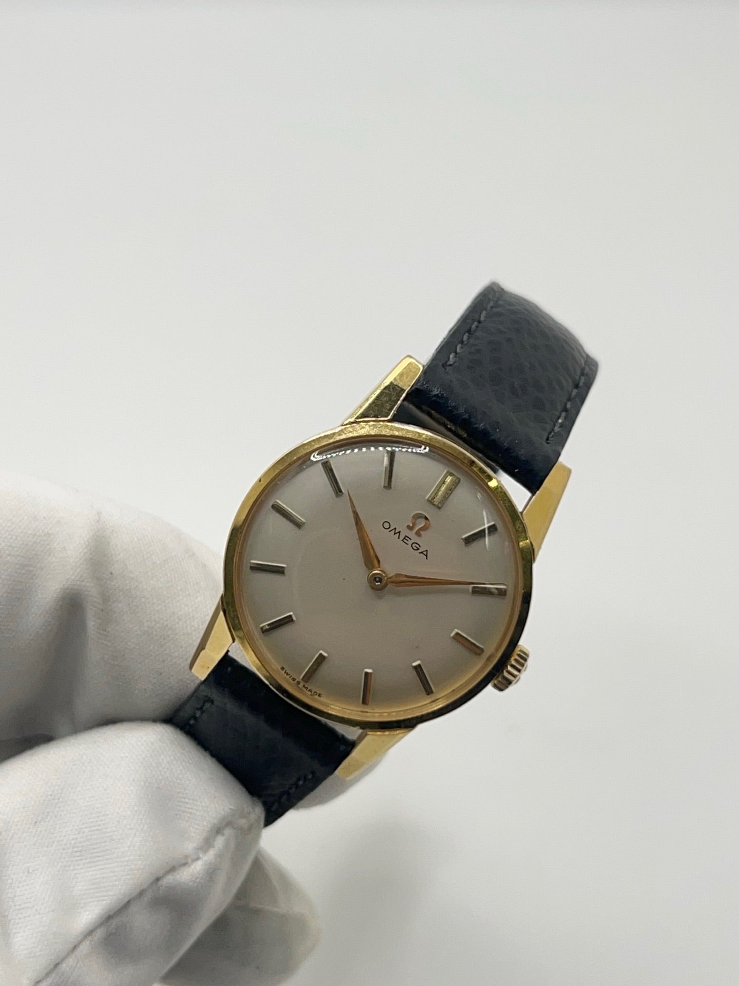 Montre femme Omega Classic vintage de 1961 en plaqué or, équipée d’un mouvement à remontage manuel. Boîtier de 25 mm avec cadran blanc à index bâtons sous verre plexiglas. Bracelet en cuir noir avec boucle ardillon en acier. Montre d’occasion en très bon état, présentant de légères micro-rayures non perceptibles au toucher. Révisée en avril 2026, sans coffret ni papiers d’origine, disponible en stock à Paris.
