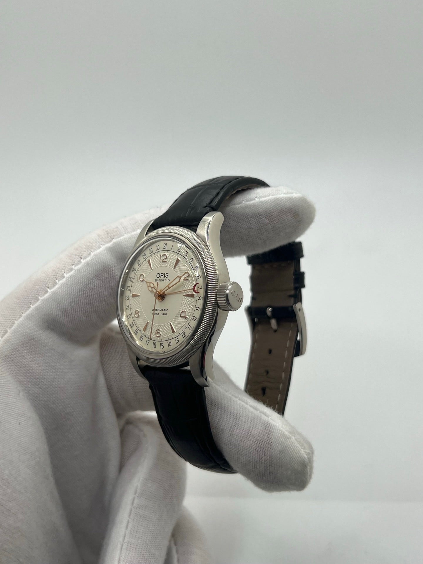 Montre mécanique automatique pour homme au style vintage, dotée d’un boîtier en acier de 36 mm et d’un cadran argent à chiffres arabes lisibles. Modèle équipé d’une fonction date par aiguille centrale, verre en matière plastique et lunette en acier. Bracelet noir avec boucle ardillon en acier. Montre d’occasion en très bon état, présentant de légères traces d’usure superficielles, récemment révisée, idéale pour les amateurs d’horlogerie classique.
