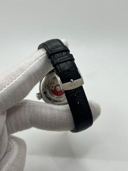 Montre mécanique automatique pour homme au style vintage, dotée d’un boîtier en acier de 36 mm et d’un cadran argent à chiffres arabes lisibles. Modèle équipé d’une fonction date par aiguille centrale, verre en matière plastique et lunette en acier. Bracelet noir avec boucle ardillon en acier. Montre d’occasion en très bon état, présentant de légères traces d’usure superficielles, récemment révisée, idéale pour les amateurs d’horlogerie classique.
