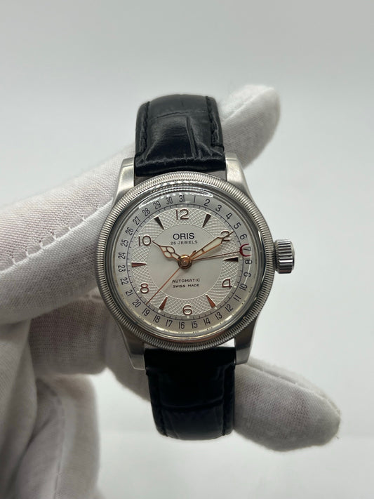 Montre mécanique automatique pour homme au style vintage, dotée d’un boîtier en acier de 36 mm et d’un cadran argent à chiffres arabes lisibles. Modèle équipé d’une fonction date par aiguille centrale, verre en matière plastique et lunette en acier. Bracelet noir avec boucle ardillon en acier. Montre d’occasion en très bon état, présentant de légères traces d’usure superficielles, récemment révisée, idéale pour les amateurs d’horlogerie classique.
