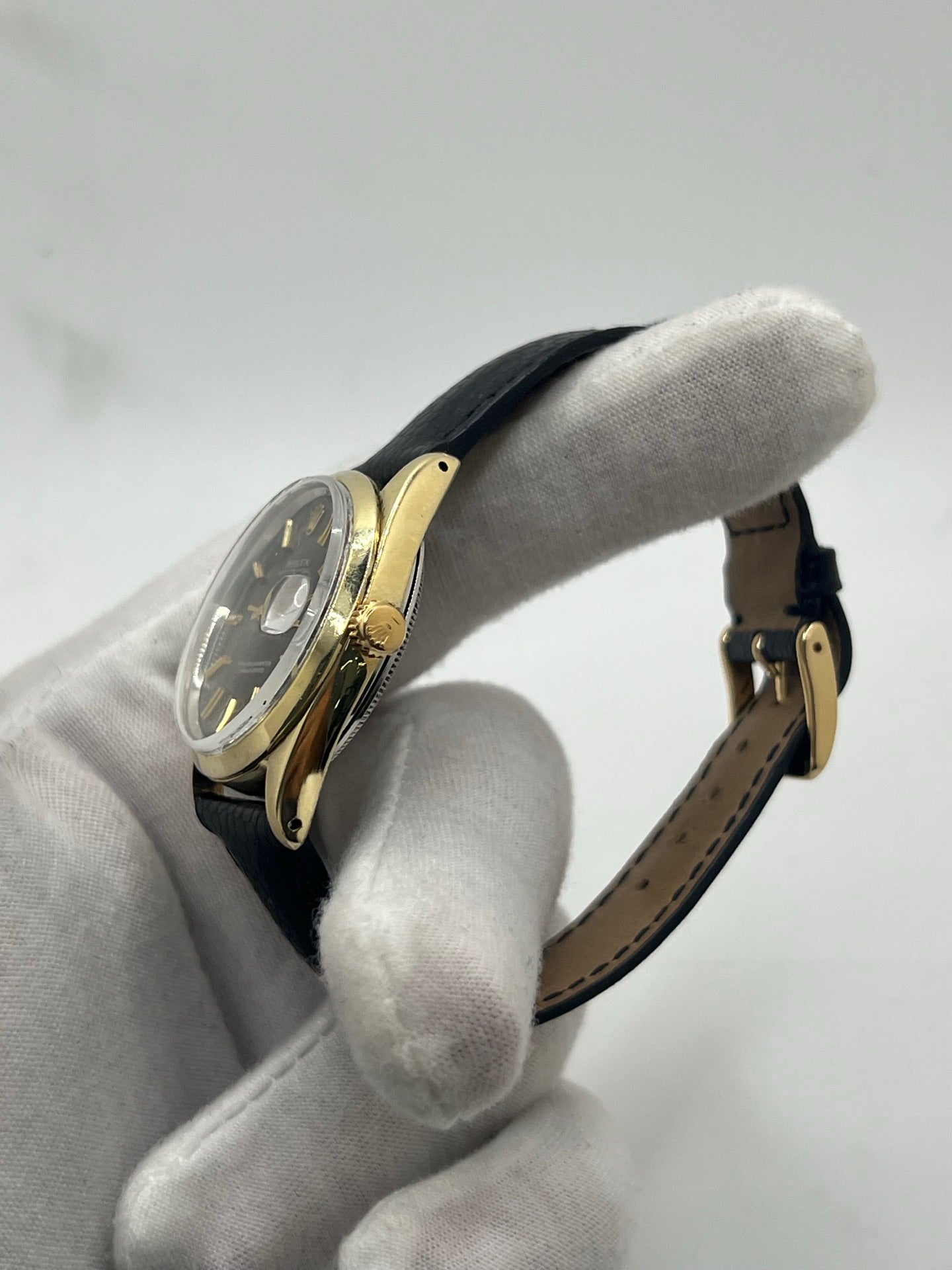 Montre Rolex Oyster Perpetual Date vintage en plaqué or, calibre automatique 1570 avec 26 pierres, cadran or et chiffres bâtons, boîtier de 34 mm, verre plexiglas. Bracelet en cuir de lézard noir avec boucle en acier. Fonction date, révision récente effectuée, coffret d’origine inclus, modèle homme/unisexe, état très bon avec légères traces d’usure.