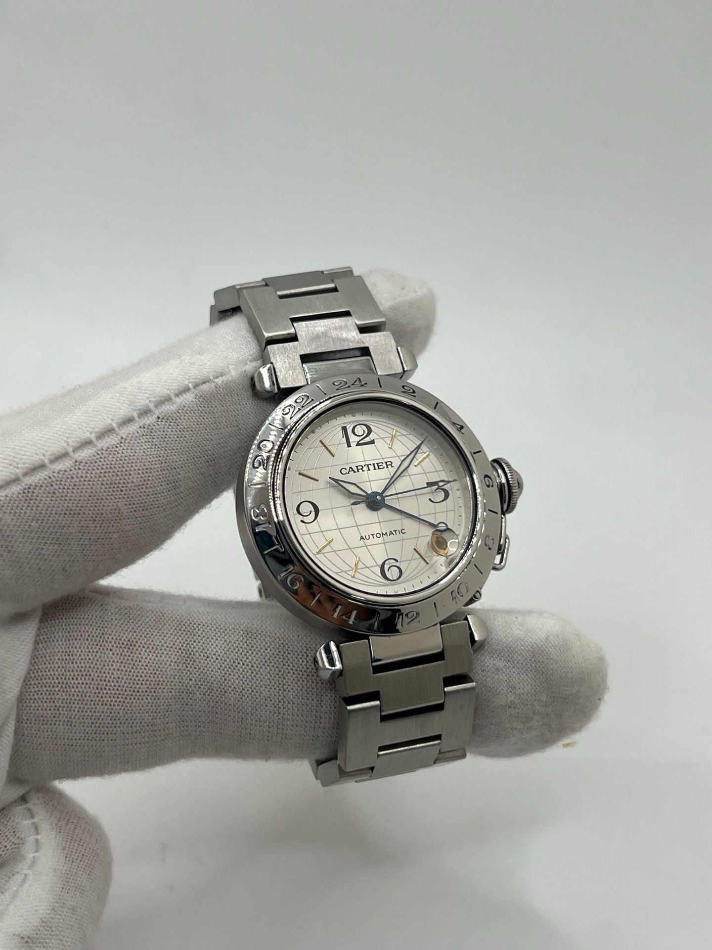 Montre Cartier Pasha C GMT réf. 2377 en acier, dotée d’un mouvement automatique calibre 048. Son boîtier de 35 mm abrite un cadran argenté à chiffres arabes, protégé par un verre saphir. Étanche jusqu’à 10 ATM, cette montre élégante et fonctionnelle est équipée d’un bracelet en acier et d’une boucle déployante double plis.