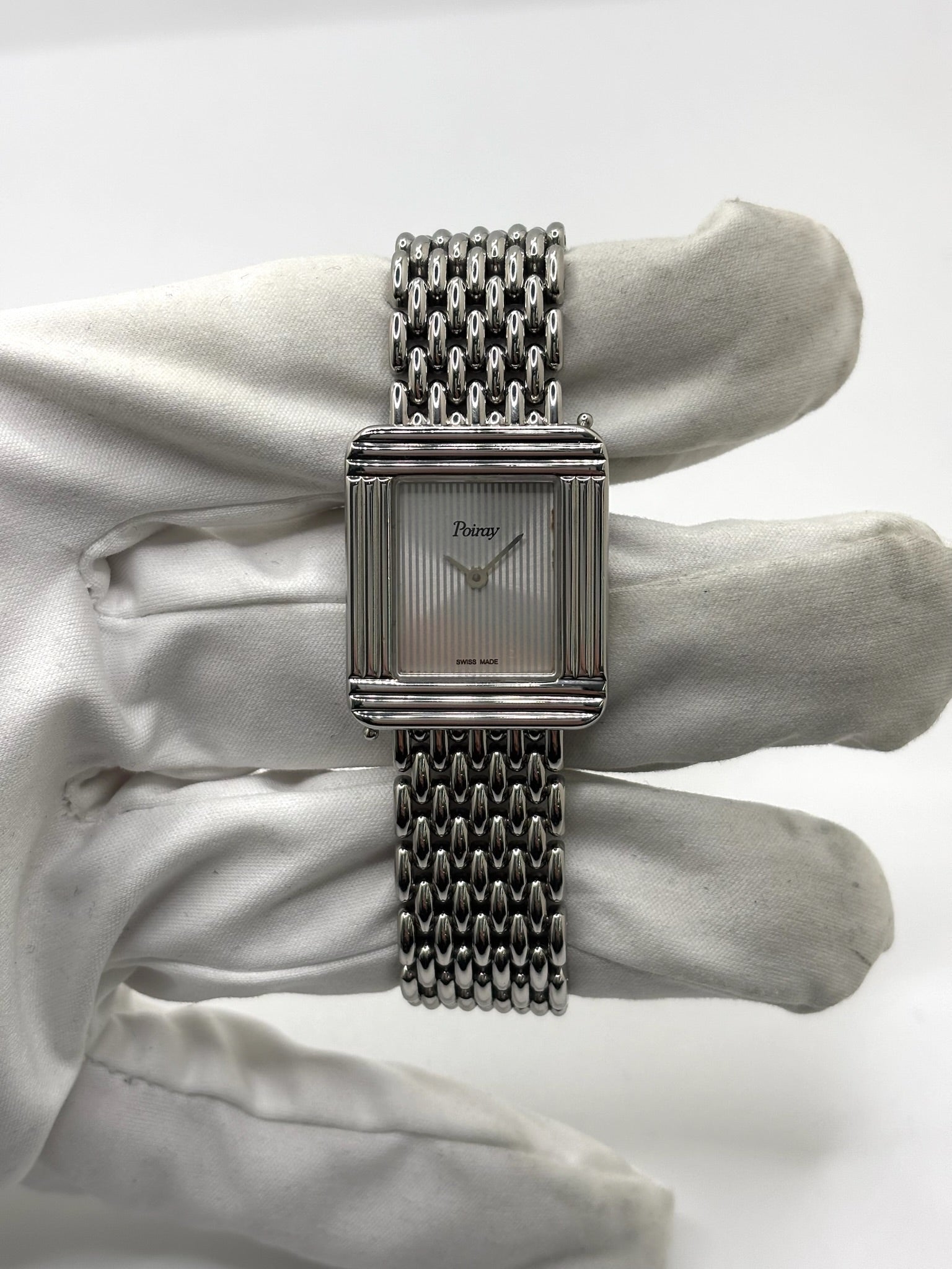 Montre Poiray Ma Première pour femme en acier inoxydable avec boîtier rectangulaire de 22,5 x 26 mm. Cette montre quartz arbore un cadran argenté protégé par un verre saphir et un bracelet en acier à boucle double pliant. Élégante et intemporelle, cette montre de luxe féminine d'occasion séduit par son design emblématique et sa finition raffinée. Modèle iconique de la maison Poiray, idéal pour les amateurs d'horlogerie et de joaillerie française.
