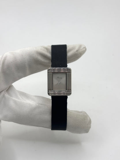 Montre Poiray Ma Première petit modèle en acier avec boîtier de 21,30 × 18,20 mm, cadran blanc épuré sans chiffres et verre minéral. Animée par un mouvement quartz, cette montre femme est équipée de son bracelet textile noir et de sa boucle ardillon d'origine en acier. Révisée, en excellent état et garantie 1 an, cette montre de luxe au style intemporel incarne l'élégance parisienne et le savoir-faire horloger de la maison Poiray.