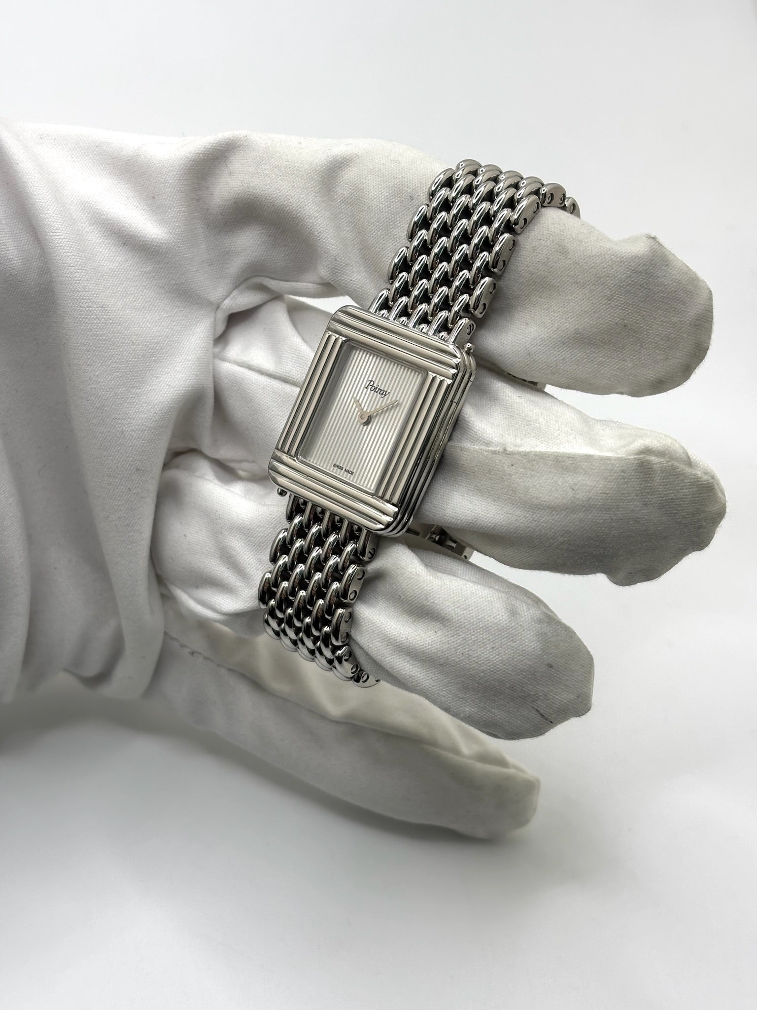 Montre Poiray Ma Première pour femme en acier inoxydable avec boîtier rectangulaire de 22,5 x 26 mm. Cette montre quartz arbore un cadran argenté protégé par un verre saphir et un bracelet en acier à boucle double pliant. Élégante et intemporelle, cette montre de luxe féminine d'occasion séduit par son design emblématique et sa finition raffinée. Modèle iconique de la maison Poiray, idéal pour les amateurs d'horlogerie et de joaillerie française.
