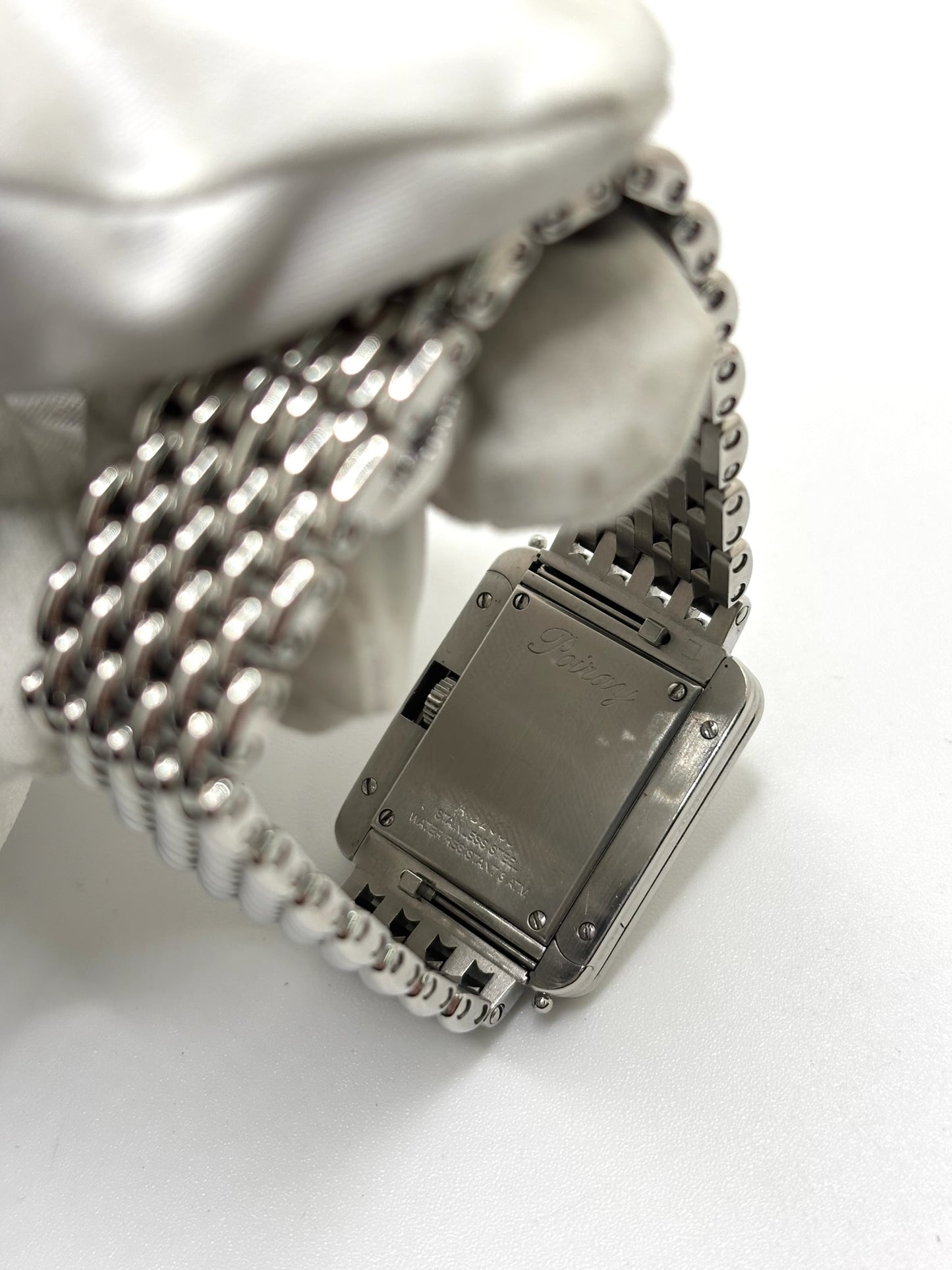 Montre Poiray Ma Première pour femme en acier inoxydable avec boîtier rectangulaire de 22,5 x 26 mm. Cette montre quartz arbore un cadran argenté protégé par un verre saphir et un bracelet en acier à boucle double pliant. Élégante et intemporelle, cette montre de luxe féminine d'occasion séduit par son design emblématique et sa finition raffinée. Modèle iconique de la maison Poiray, idéal pour les amateurs d'horlogerie et de joaillerie française.
