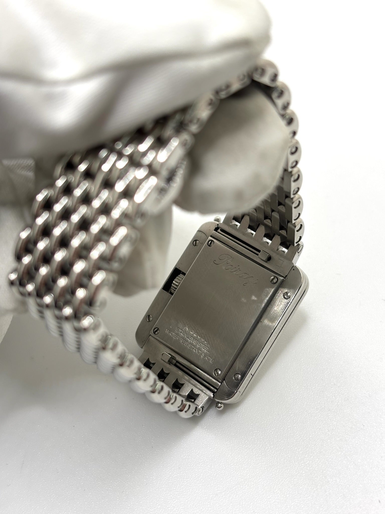 Montre Poiray Ma Première pour femme en acier inoxydable avec boîtier rectangulaire de 22,5 x 26 mm. Cette montre quartz arbore un cadran argenté protégé par un verre saphir et un bracelet en acier à boucle double pliant. Élégante et intemporelle, cette montre de luxe féminine d'occasion séduit par son design emblématique et sa finition raffinée. Modèle iconique de la maison Poiray, idéal pour les amateurs d'horlogerie et de joaillerie française.
