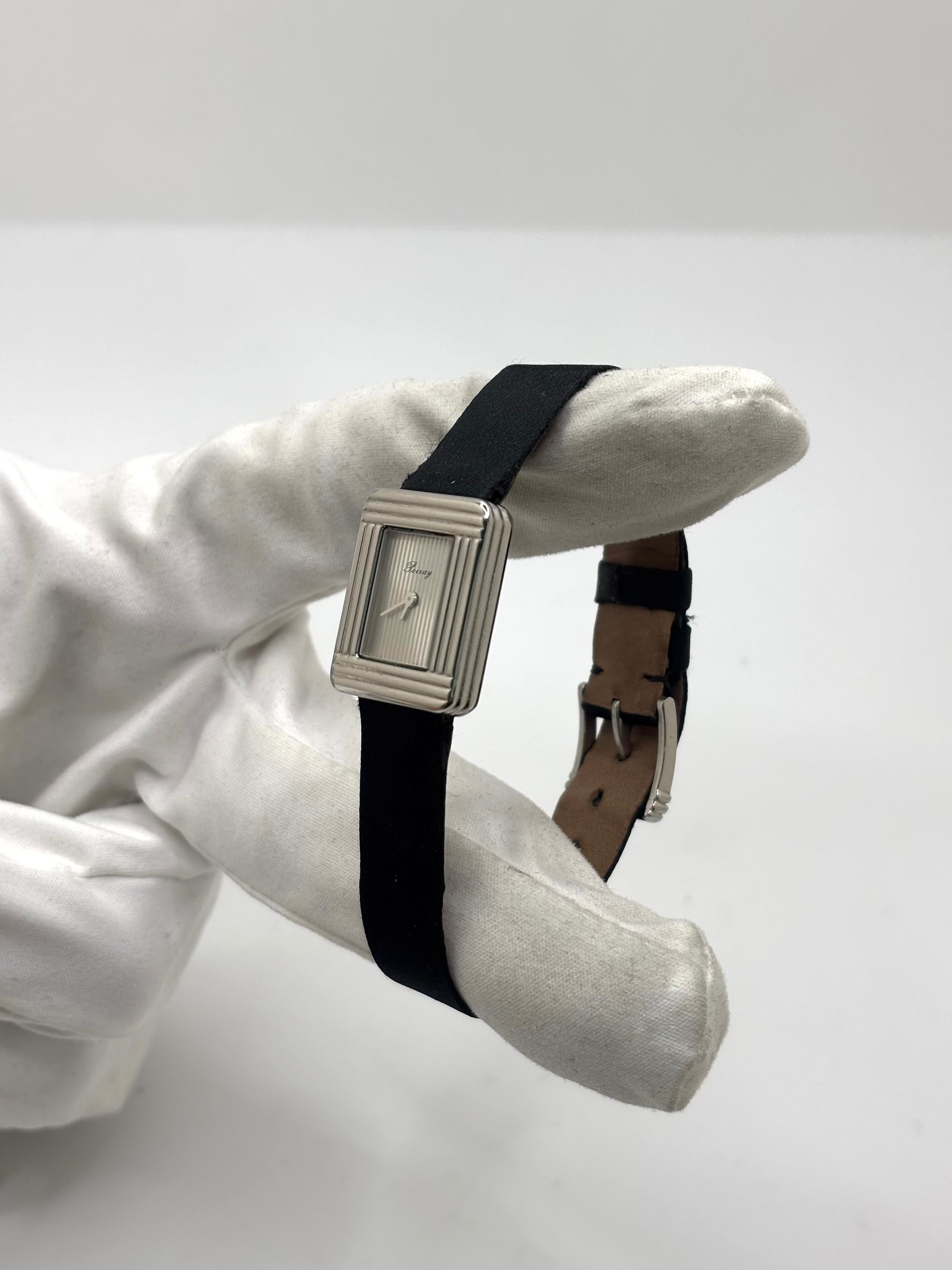 Montre Poiray Ma Première petit modèle en acier avec boîtier de 21,30 × 18,20 mm, cadran blanc épuré sans chiffres et verre minéral. Animée par un mouvement quartz, cette montre femme est équipée de son bracelet textile noir et de sa boucle ardillon d'origine en acier. Révisée, en excellent état et garantie 1 an, cette montre de luxe au style intemporel incarne l'élégance parisienne et le savoir-faire horloger de la maison Poiray.