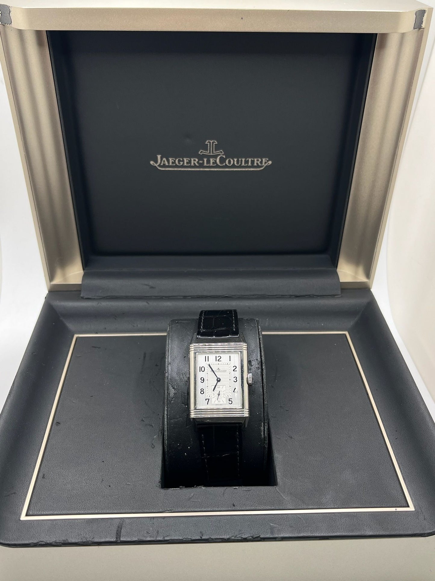 Montre Jaeger-LeCoultre Reverso Classic Small/Large réf. 214.8.62, modèle emblématique de 2017, livrée en full set avec boîte et papiers d’origine. Équipée d’une élégante boucle déployante, cette montre mécanique incarne le savoir-faire horloger suisse. Boîtier rectangulaire en acier, mouvement à remontage manuel. Une pièce raffinée pour collectionneur ou amateur de montres de prestige.