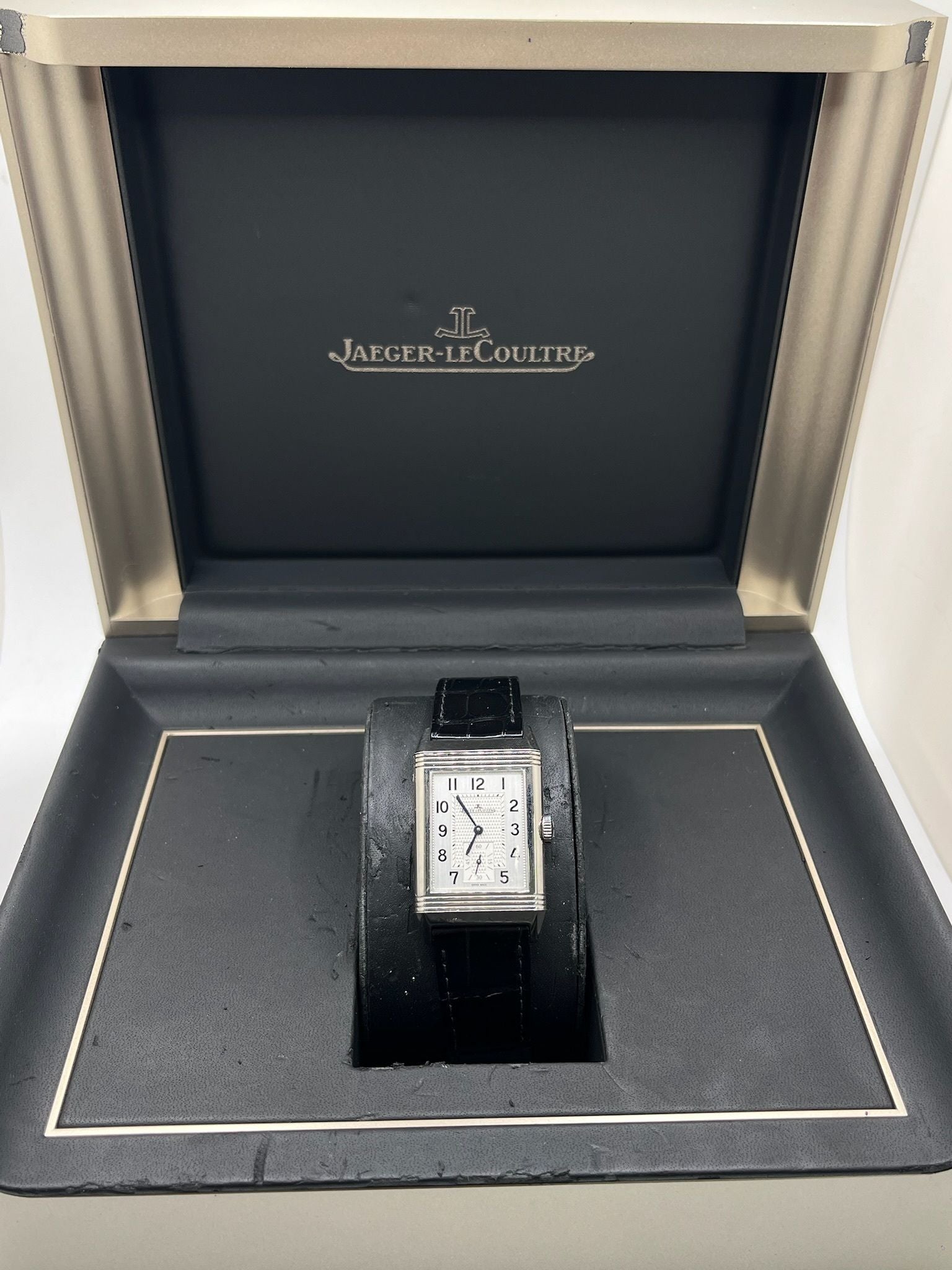 Montre Jaeger-LeCoultre Reverso Classic Small/Large réf. 214.8.62, modèle emblématique de 2017, livrée en full set avec boîte et papiers d’origine. Équipée d’une élégante boucle déployante, cette montre mécanique incarne le savoir-faire horloger suisse. Boîtier rectangulaire en acier, mouvement à remontage manuel. Une pièce raffinée pour collectionneur ou amateur de montres de prestige.
