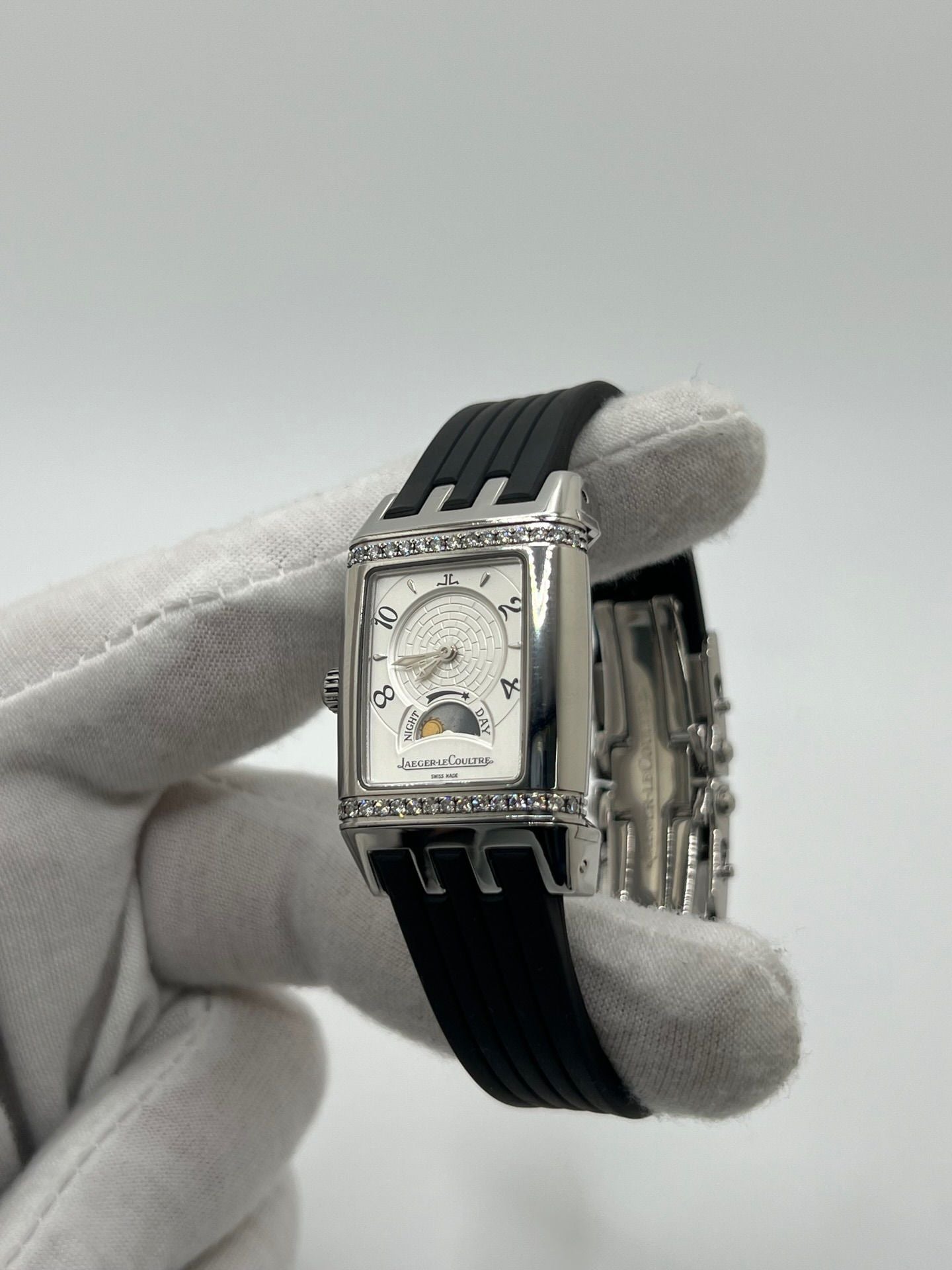 Montre Reverso Duetto référence 296.8.74 en acier, format rectangulaire, équipée d’un mouvement à remontage manuel. Modèle pour femme avec cadran blanc à chiffres arabes et verre saphir. Brace­let en caoutchouc noir avec boucle double plis. Pièce d’occasion en très bon état, présentant de légères traces d’usure discrètes.