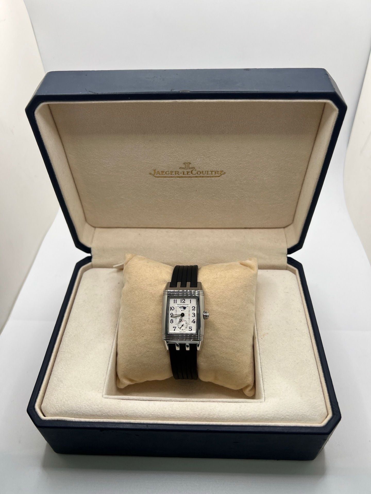 Montre Reverso Duetto référence 296.8.74 en acier, format rectangulaire, équipée d’un mouvement à remontage manuel. Modèle pour femme avec cadran blanc à chiffres arabes et verre saphir. Brace­let en caoutchouc noir avec boucle double plis. Pièce d’occasion en très bon état, présentant de légères traces d’usure discrètes.