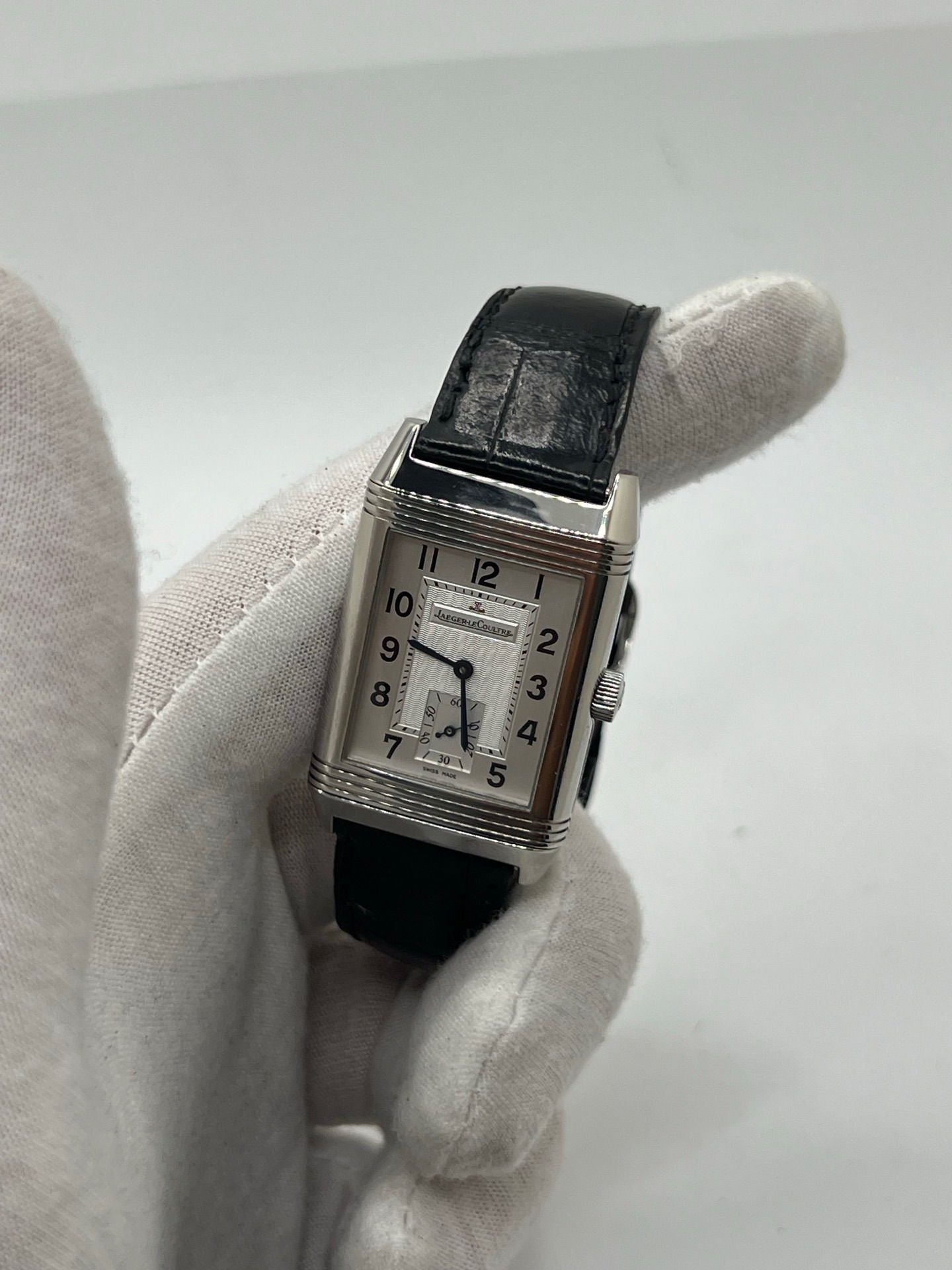 Découvrez la Jaeger-LeCoultre Reverso Grande Taille pour homme/unisexe, modèle 2008 en acier avec bracelet cuir brun. Montre de luxe à remontage manuel, calibre 822, 45 h de réserve de marche, petite seconde et cadran argent. État très bon, avec coffret et papiers d’origine.
