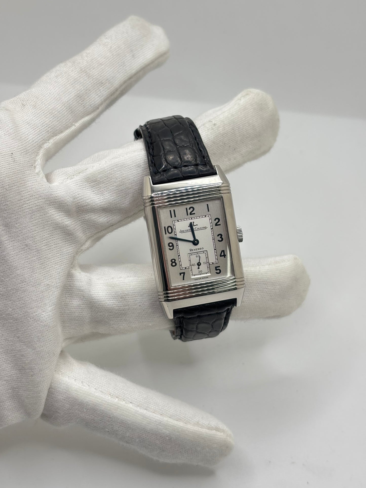 Montre Jaeger-LeCoultre Reverso Grande Taille 270.8.62 en acier, mouvement mécanique à remontage manuel calibre 822. Boîtier rectangulaire 26 x 42 mm, cadran argent à chiffres arabes, petite seconde, verre saphir. Bracelet cuir noir boucle ardillon acier. Modèle 1997 en très bon état, révisé le 4 juin 2026, livré avec coffret et papiers d’origine. Montre de luxe suisse emblématique, design Art déco, style vintage élégant. pièce horlogère iconique.

