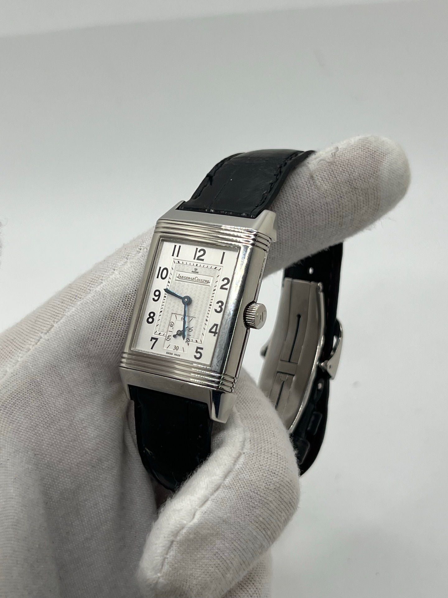Découvrez la Jaeger-LeCoultre Reverso Grande Taille pour homme/unisexe, modèle 2008 en acier avec bracelet cuir brun. Montre de luxe à remontage manuel, calibre 822, 45 h de réserve de marche, petite seconde et cadran argent. État très bon, avec coffret et papiers d’origine.