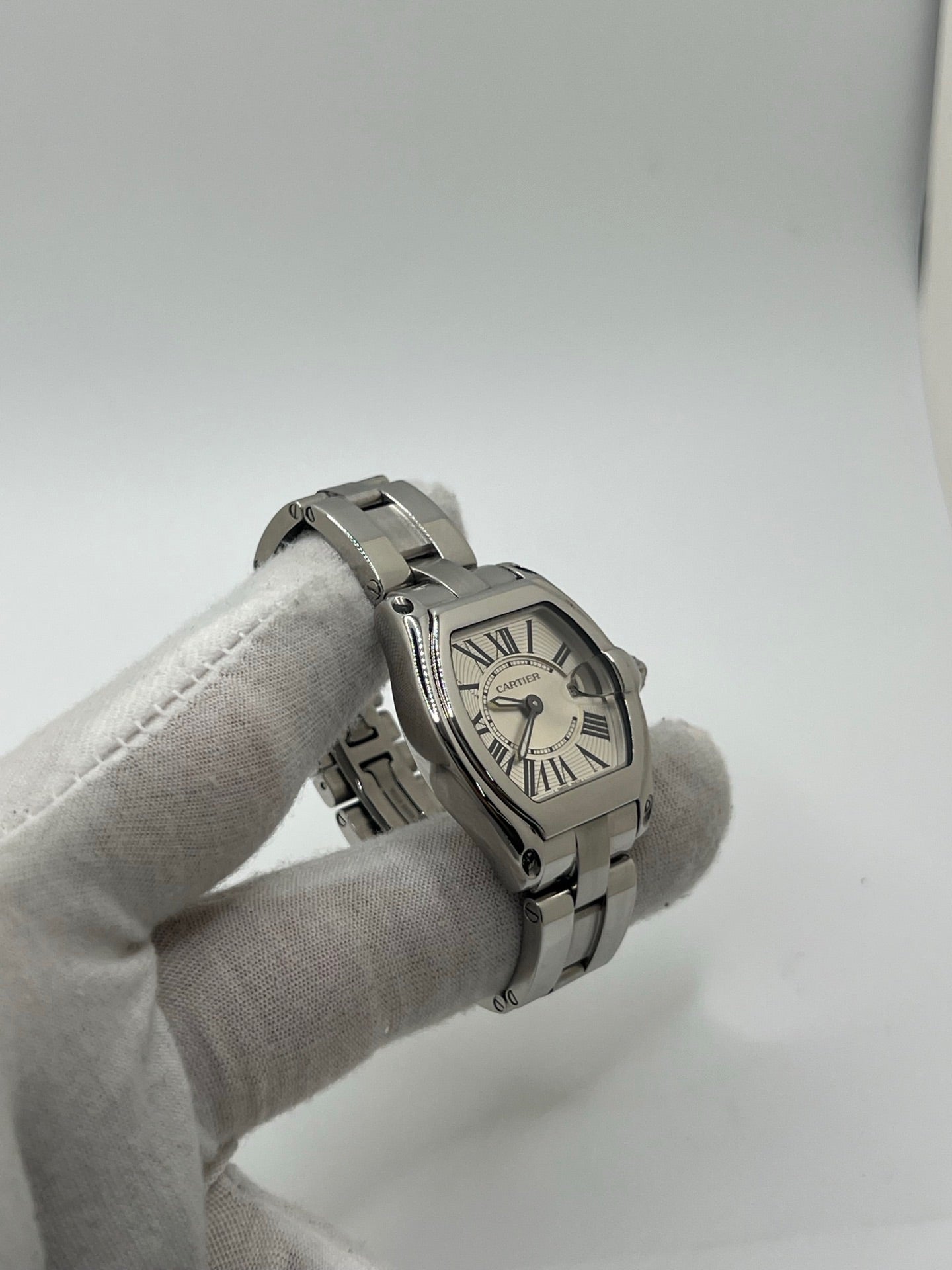 Montre Cartier Roadster 2675 pour femme en acier, équipée d’un mouvement quartz calibre 688. Boîtier 31 x 37 mm avec verre saphir, cadran argent à chiffres romains et bracelet acier à boucle déployante. Modèle étanche à 10 ATM avec fonction date, livré avec coffret d’origine, en très bon état d’occasion.