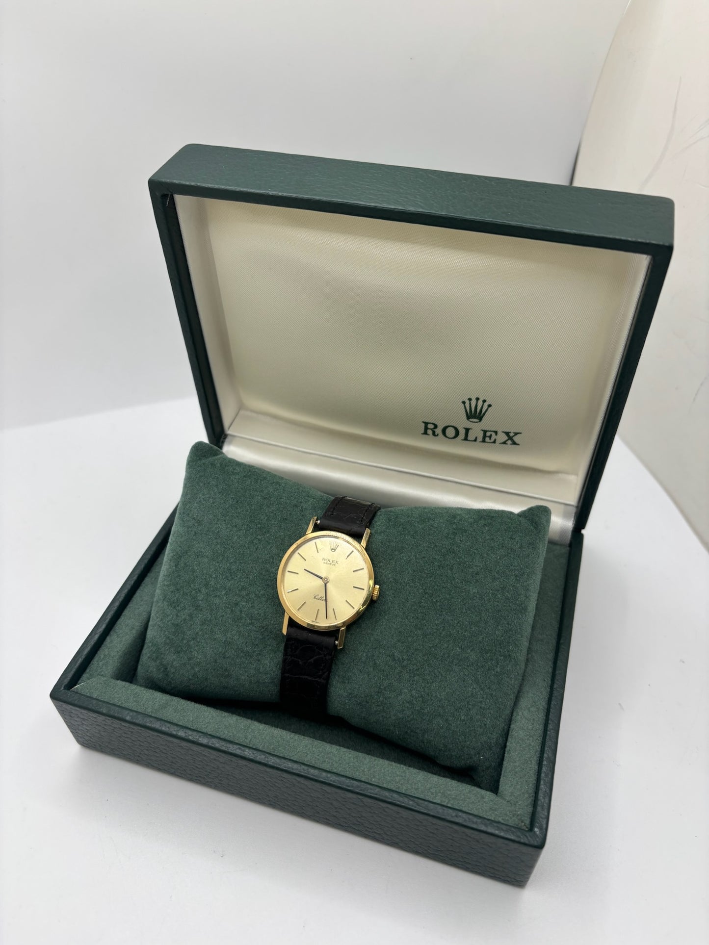 Montre Rolex Cellini référence 4109 vintage en or jaune de 1976, équipée d’un mouvement à remontage manuel calibre 1601. Boîtier de 26 mm en or jaune avec lunette assortie, cadran doré à index bâtons et verre saphir. Bracelet en cuir noir avec boucle ardillon en acier. Montre femme élégante d’occasion en bon état présentant des traces d’usure visibles (rayures et petites marques). Révisée en interne le 30 juin 2026, livrée avec coffret d’origine sans papiers.