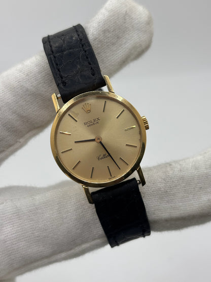 Montre Rolex Cellini référence 4109 vintage en or jaune de 1976, équipée d’un mouvement à remontage manuel calibre 1601. Boîtier de 26 mm en or jaune avec lunette assortie, cadran doré à index bâtons et verre saphir. Bracelet en cuir noir avec boucle ardillon en acier. Montre femme élégante d’occasion en bon état présentant des traces d’usure visibles (rayures et petites marques). Révisée en interne le 30 juin 2026, livrée avec coffret d’origine sans papiers.