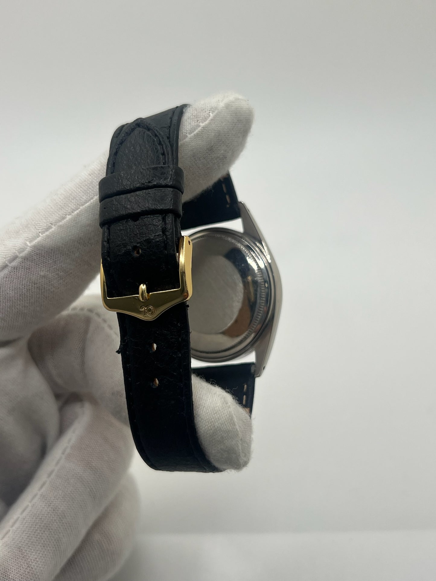 Montre Rolex Datejust automatique vintage de 36 mm en acier avec lunette en or jaune, cadran noir épuré sans chiffres et affichage de la date à 3 heures. Boîtier élégant protégé par un verre plexiglas, étanche jusqu’à 10 ATM. Bracelet en cuir noir avec boucle en acier. Mouvement mécanique à remontage automatique offrant environ 40 heures de réserve de marche. Modèle des années 1960, en très bon état, présentant de légères traces d’usure superficielles.