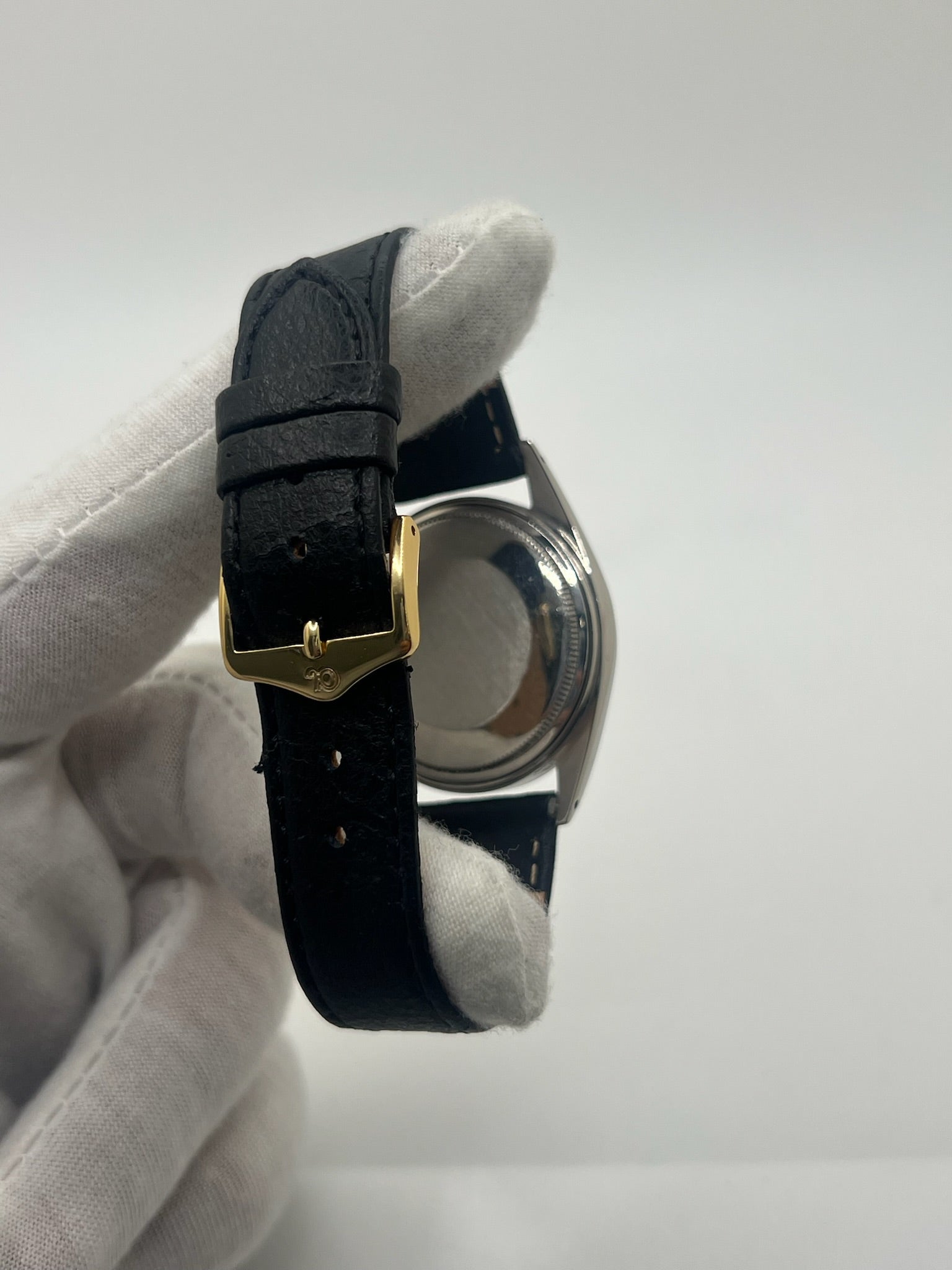 Montre Rolex Datejust automatique vintage de 36 mm en acier avec lunette en or jaune, cadran noir épuré sans chiffres et affichage de la date à 3 heures. Boîtier élégant protégé par un verre plexiglas, étanche jusqu’à 10 ATM. Bracelet en cuir noir avec boucle en acier. Mouvement mécanique à remontage automatique offrant environ 40 heures de réserve de marche. Modèle des années 1960, en très bon état, présentant de légères traces d’usure superficielles.