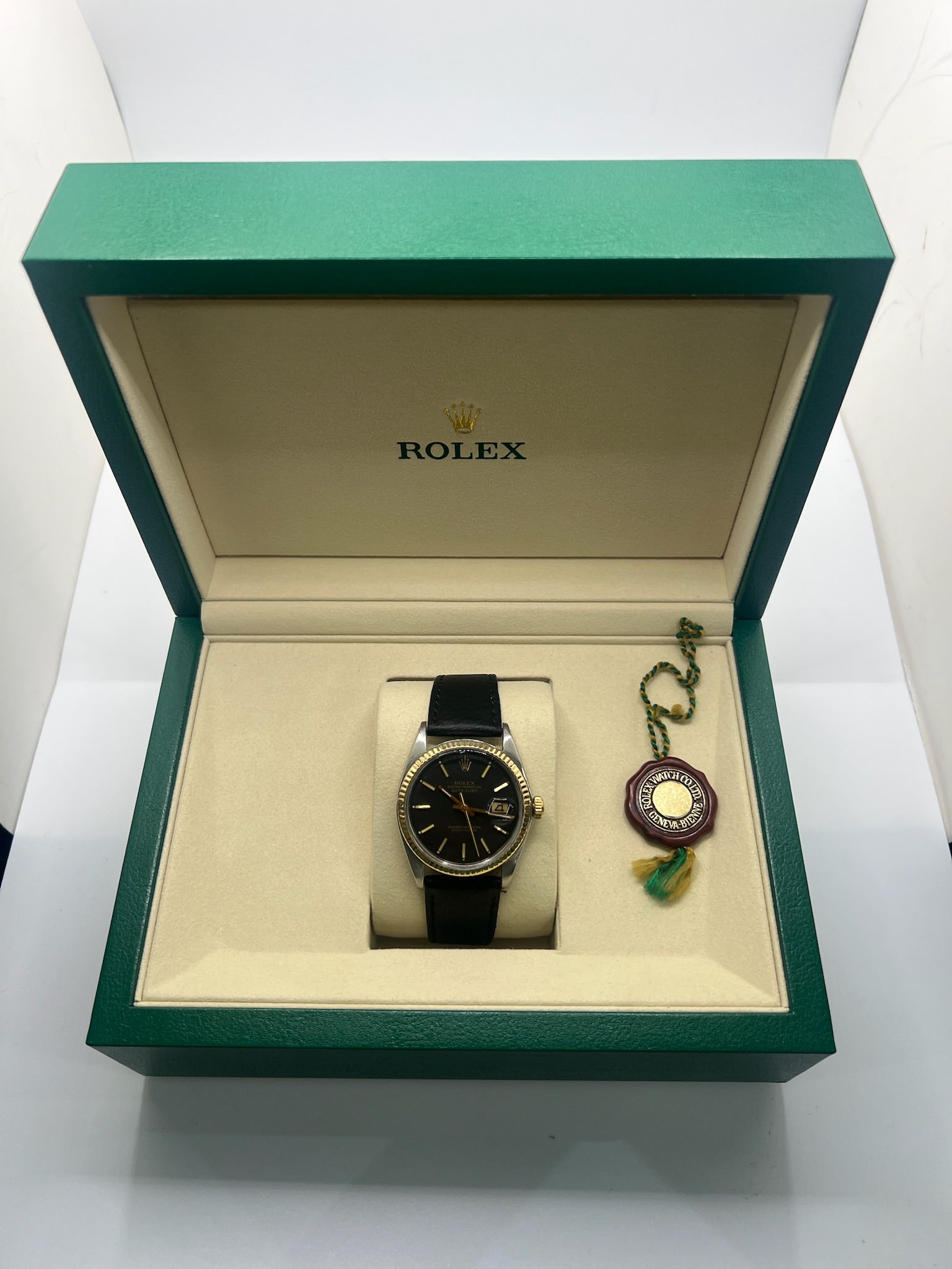 Montre Rolex Datejust automatique vintage de 36 mm en acier avec lunette en or jaune, cadran noir épuré sans chiffres et affichage de la date à 3 heures. Boîtier élégant protégé par un verre plexiglas, étanche jusqu’à 10 ATM. Bracelet en cuir noir avec boucle en acier. Mouvement mécanique à remontage automatique offrant environ 40 heures de réserve de marche. Modèle des années 1960, en très bon état, présentant de légères traces d’usure superficielles.