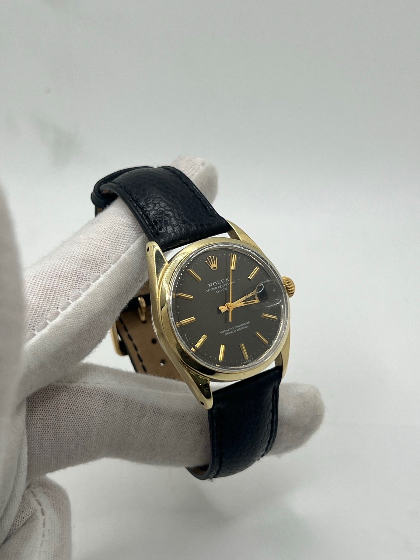 Montre Rolex Oyster Perpetual Date vintage en plaqué or, calibre automatique 1570 avec 26 pierres, cadran or et chiffres bâtons, boîtier de 34 mm, verre plexiglas. Bracelet en cuir de lézard noir avec boucle en acier. Fonction date, révision récente effectuée, coffret d’origine inclus, modèle homme/unisexe, état très bon avec légères traces d’usure.