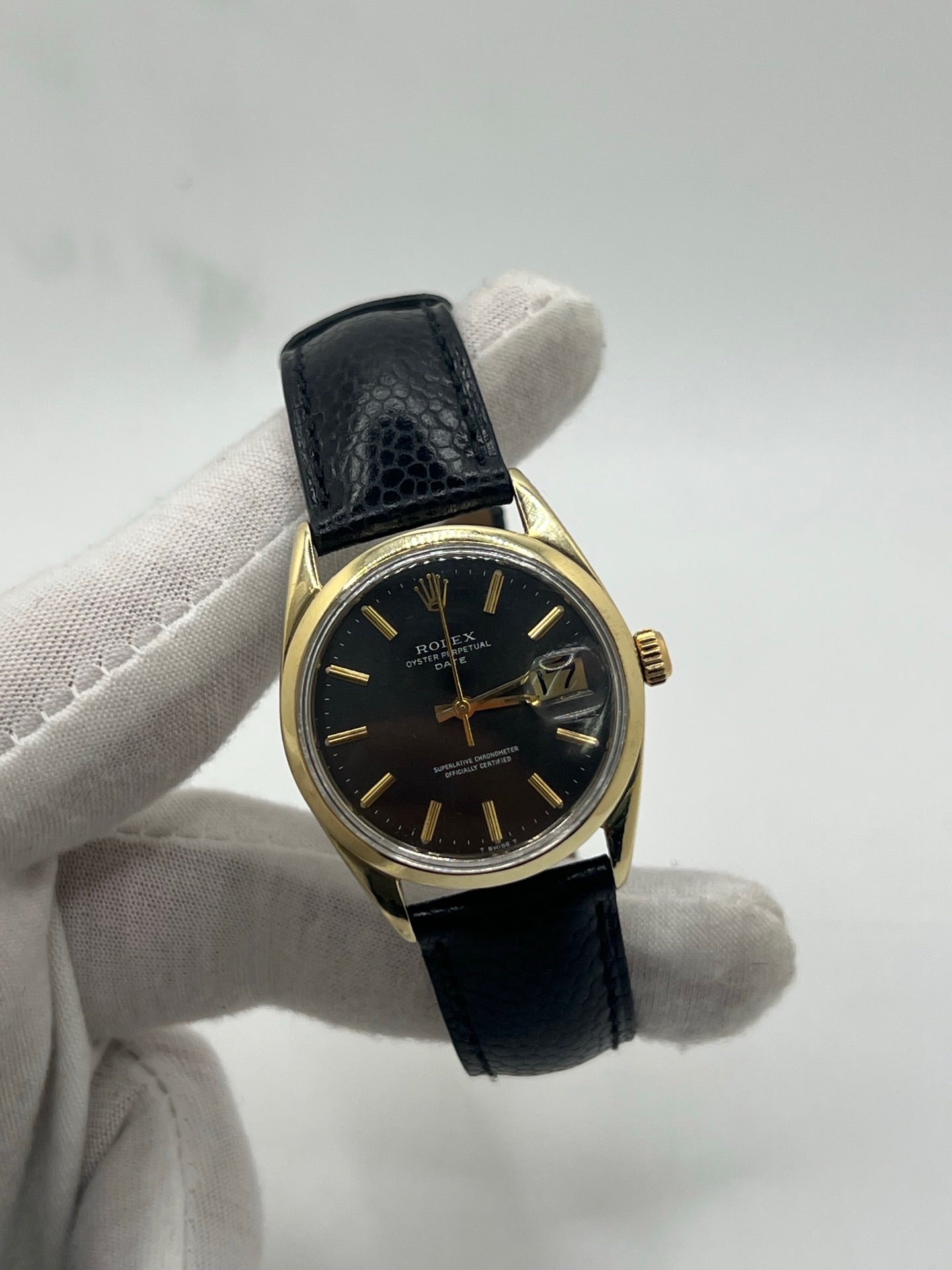 Montre Rolex Oyster Perpetual Date vintage en plaqué or, calibre automatique 1570 avec 26 pierres, cadran or et chiffres bâtons, boîtier de 34 mm, verre plexiglas. Bracelet en cuir de lézard noir avec boucle en acier. Fonction date, révision récente effectuée, coffret d’origine inclus, modèle homme/unisexe, état très bon avec légères traces d’usure.