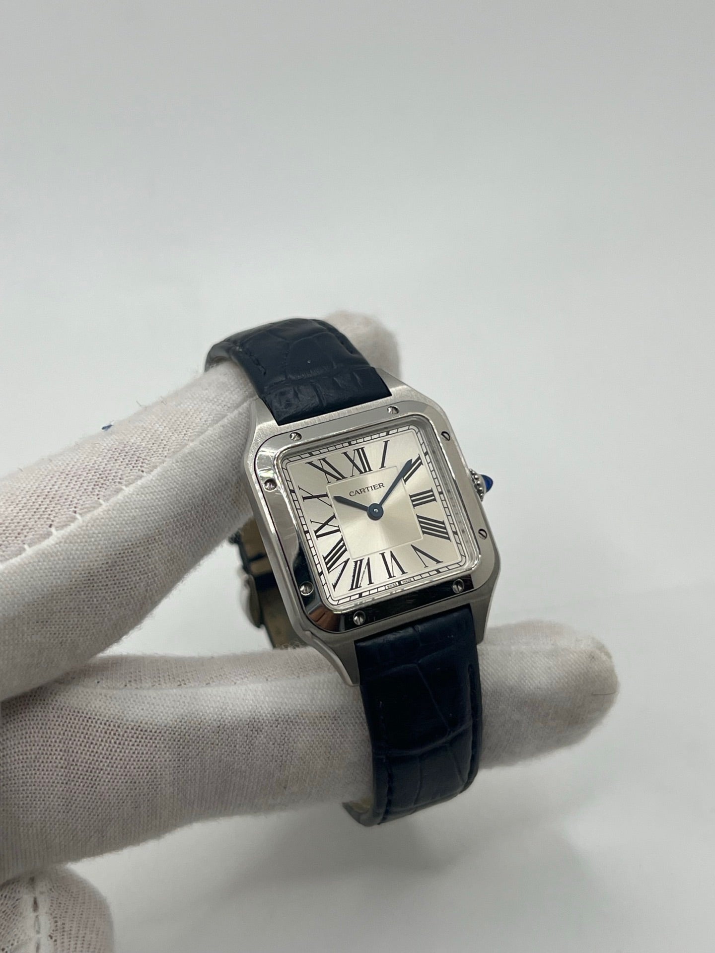 Montre élégante Santos Dumont en acier avec cadran argent et chiffres romains, équipée d’un mouvement quartz précis. Bracelet en cuir de crocodile bleu avec boucle ardillon en acier. Boîtier 38 x 27,5 mm, verre saphir et étanchéité 3 ATM. Design raffiné, idéal pour un style classique et sophistiqué. Disponible avec coffret et papiers d’origine.