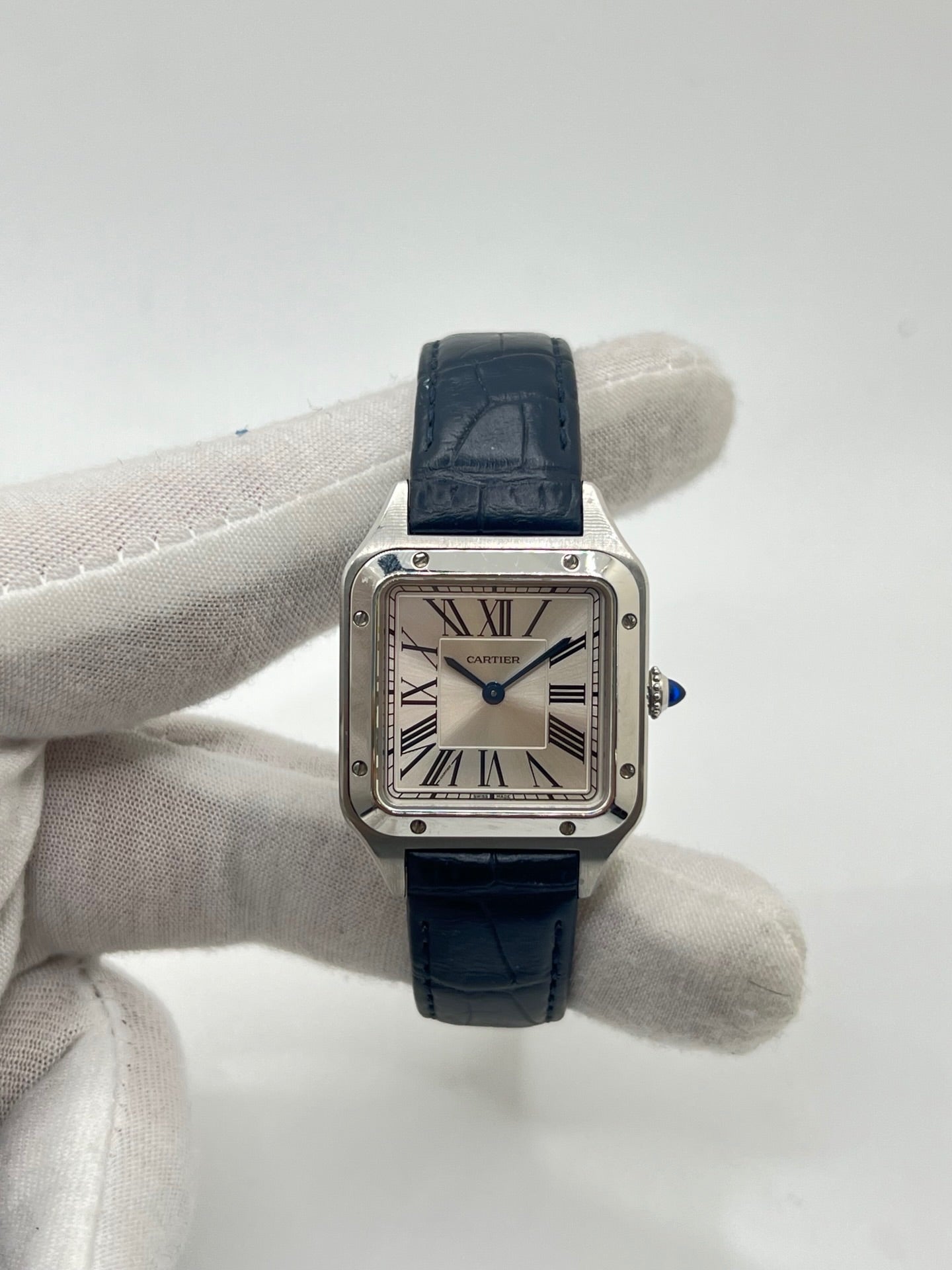 Montre élégante Santos Dumont en acier avec cadran argent et chiffres romains, équipée d’un mouvement quartz précis. Bracelet en cuir de crocodile bleu avec boucle ardillon en acier. Boîtier 38 x 27,5 mm, verre saphir et étanchéité 3 ATM. Design raffiné, idéal pour un style classique et sophistiqué. Disponible avec coffret et papiers d’origine.